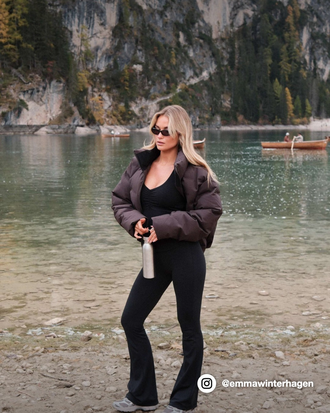 Woman wearing a cocoa bean CASPARA Aurora puffer jacket standing by an alpine lake.