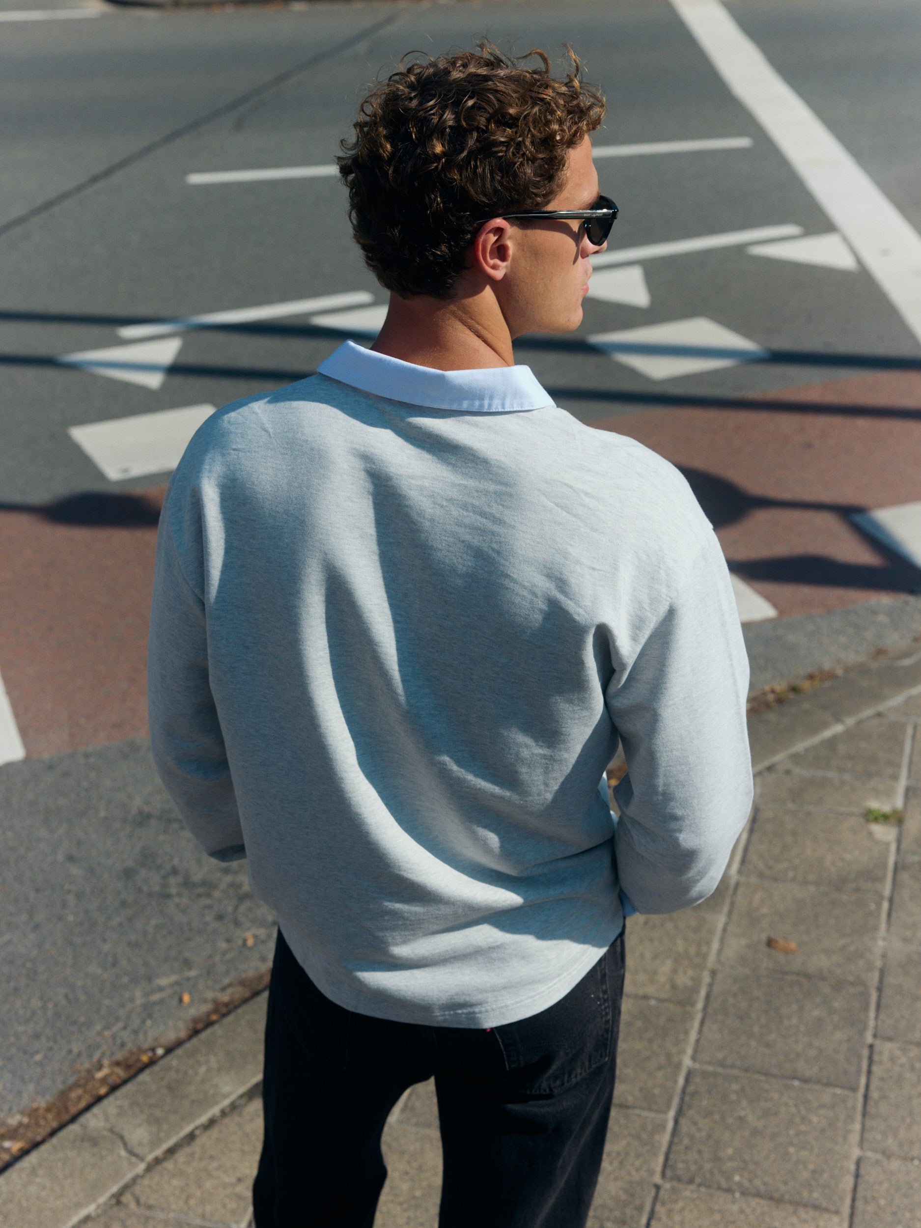 Back view of a man wearing a light grey cotton rugby shirt with a white collar.
