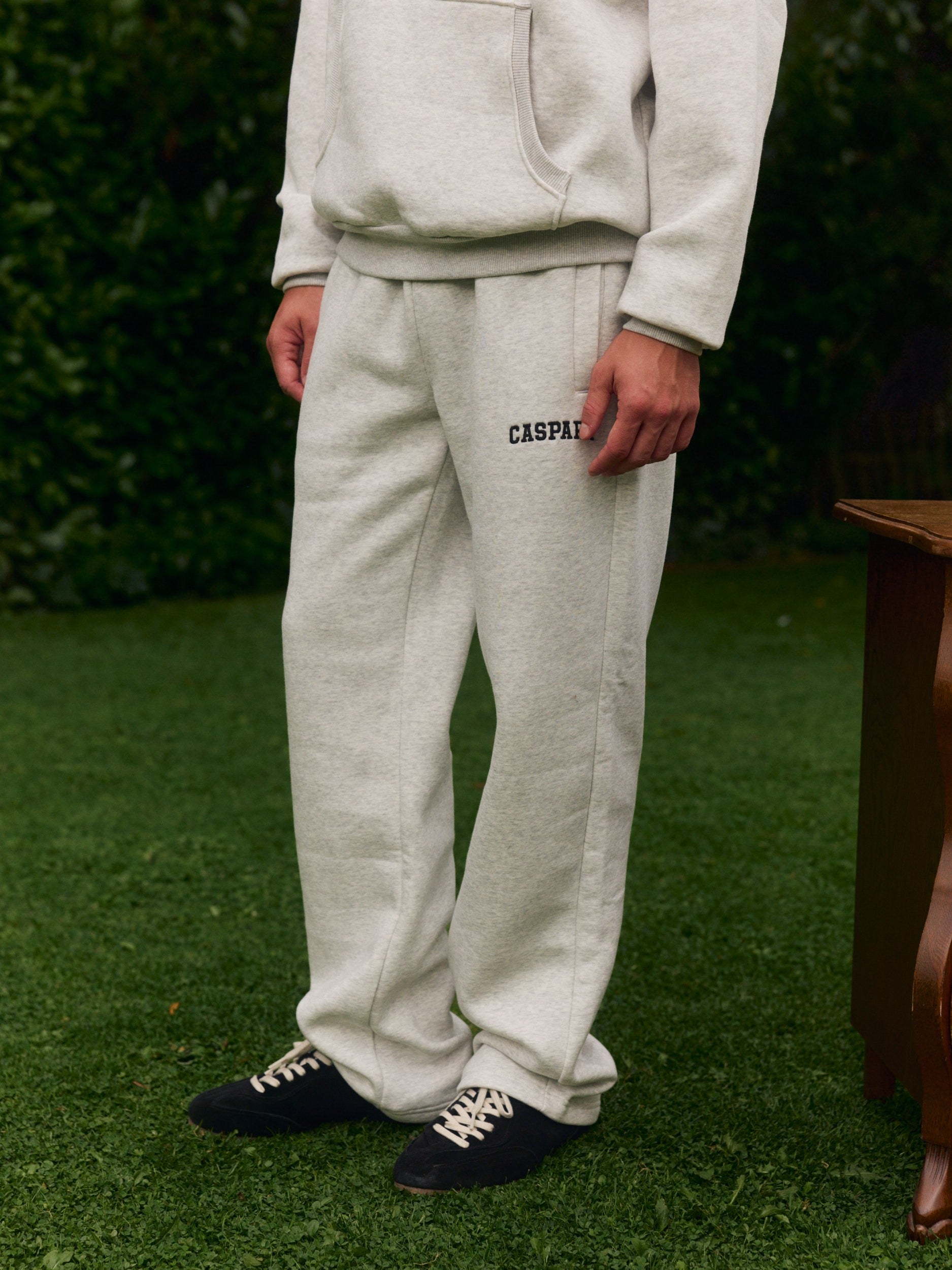 Man wearing grey melange straight-leg sweatpants standing outdoors on a green lawn.