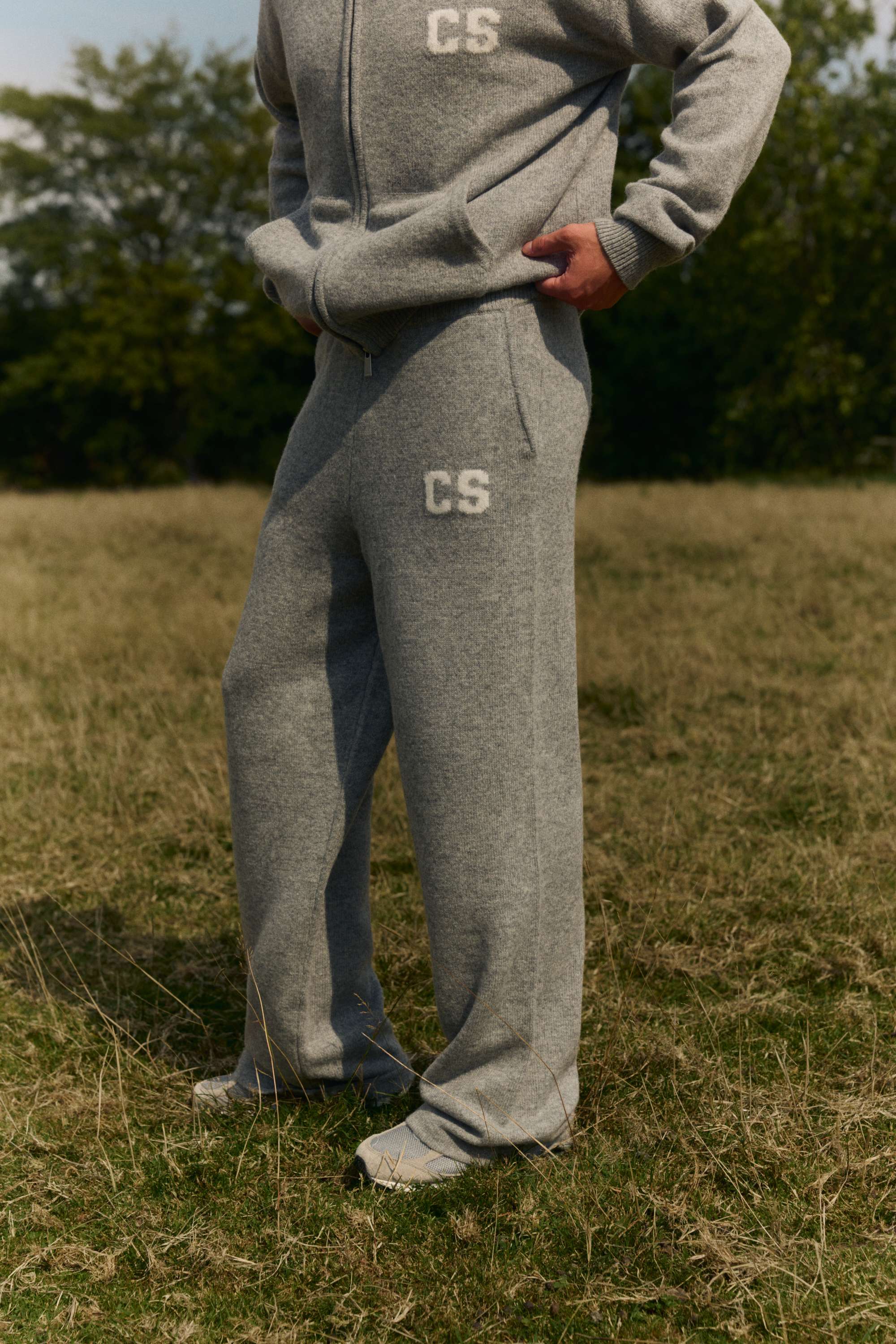 Man wearing dark grey melange woolknit straight leg pants and matching zip hoodie outdoors.