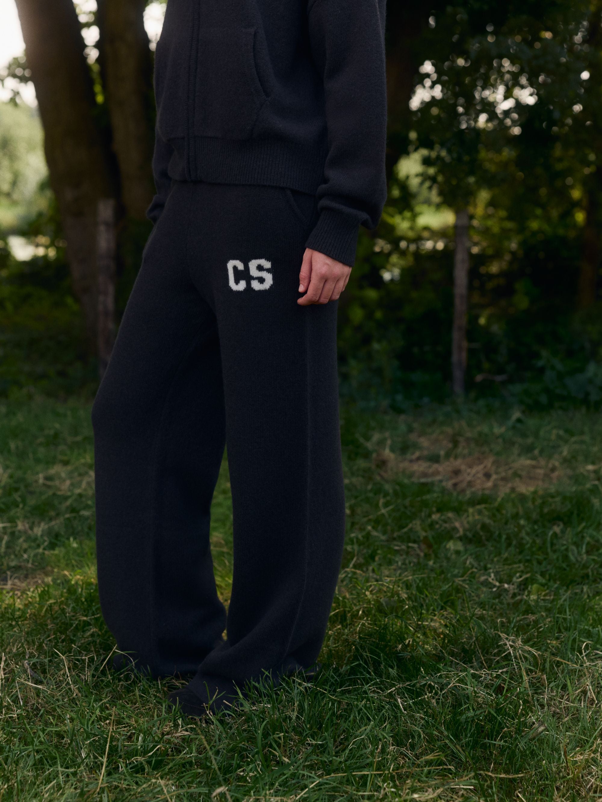Woman wearing cocoa bean CASPARA woolknit straight leg pants with a white CS logo outdoors.