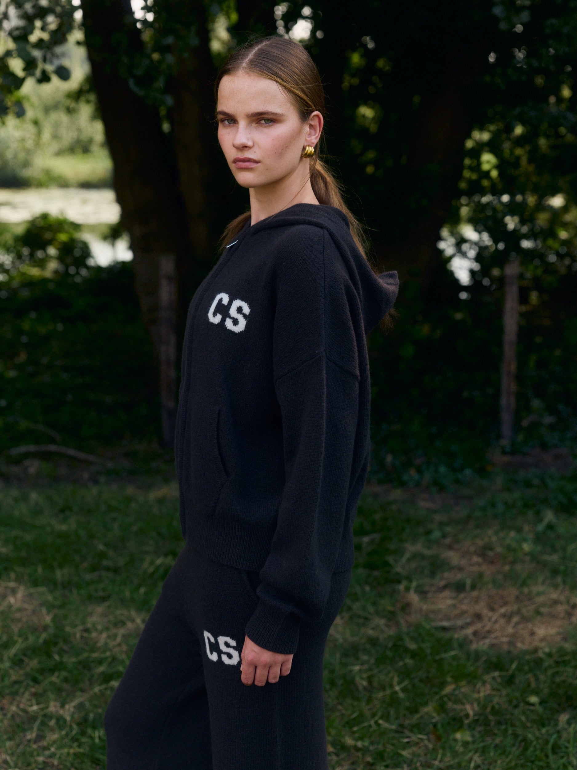 Woman wearing a cocoa bean wool knit zip jacket and matching pants outdoors.