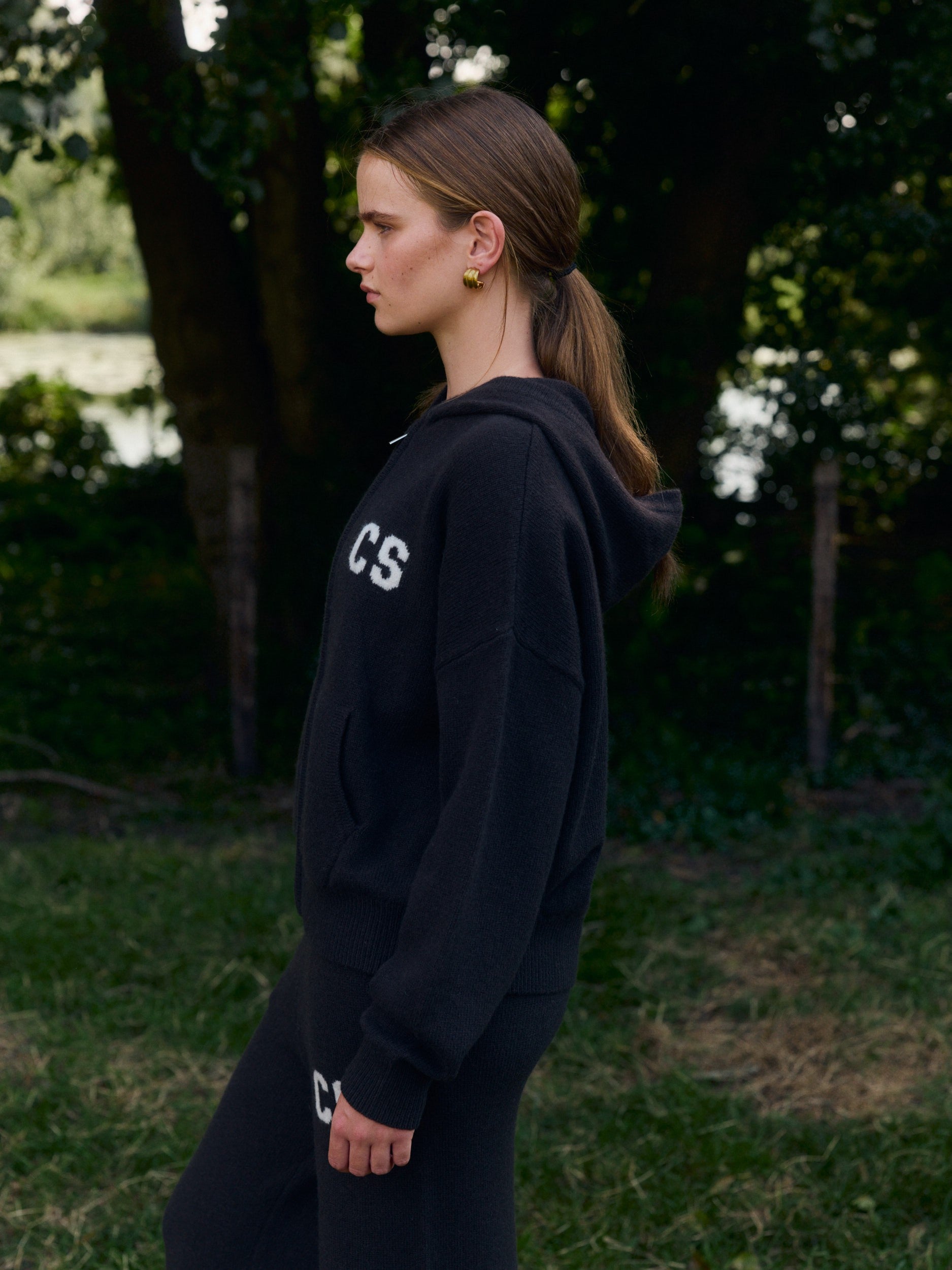 Woman wearing a cocoa bean woolknit zip jacket and pants standing outdoors.