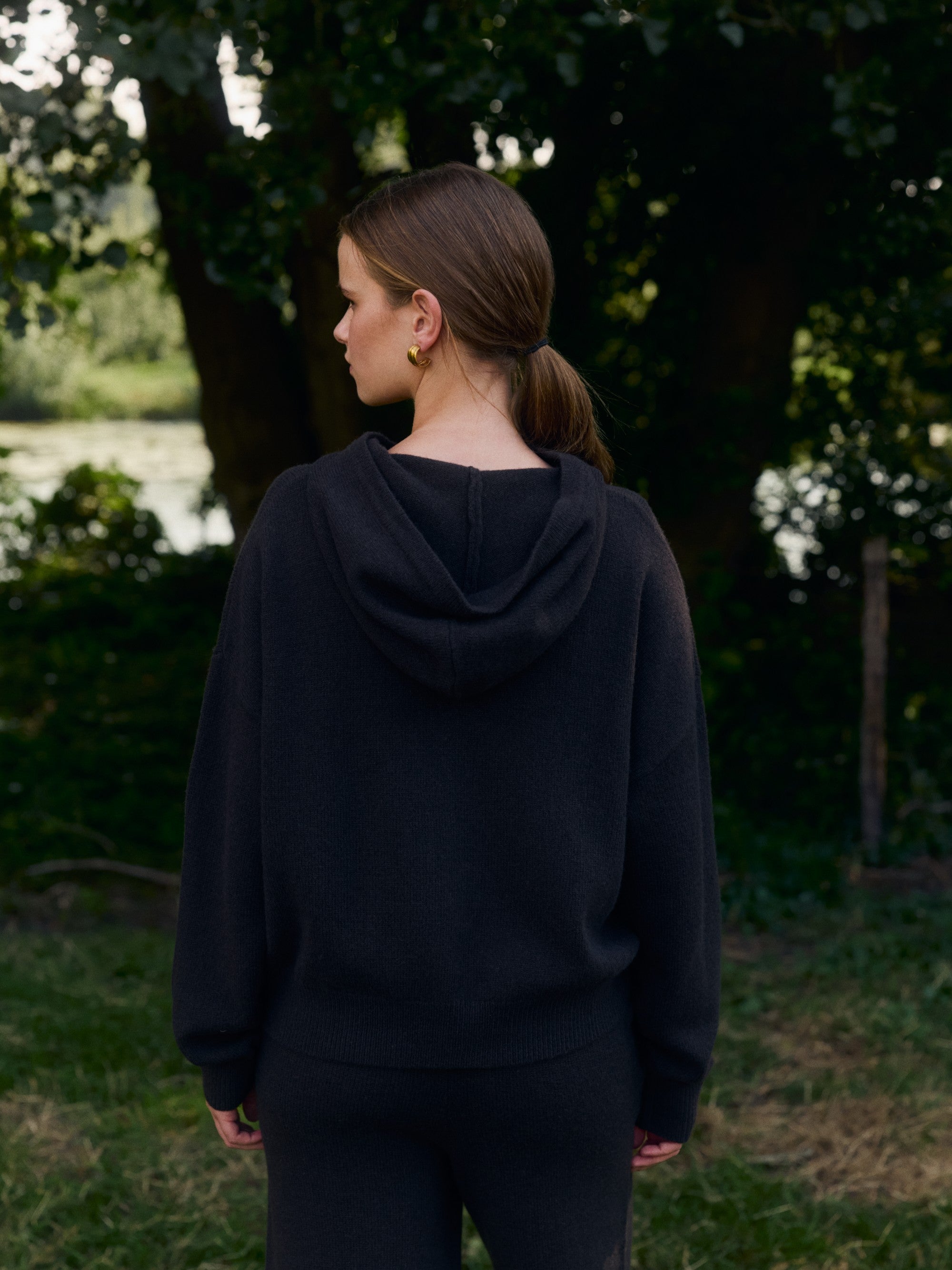 Woman wearing the CASPARA cocoa bean Woolknit zip jacket from behind in an outdoor setting.