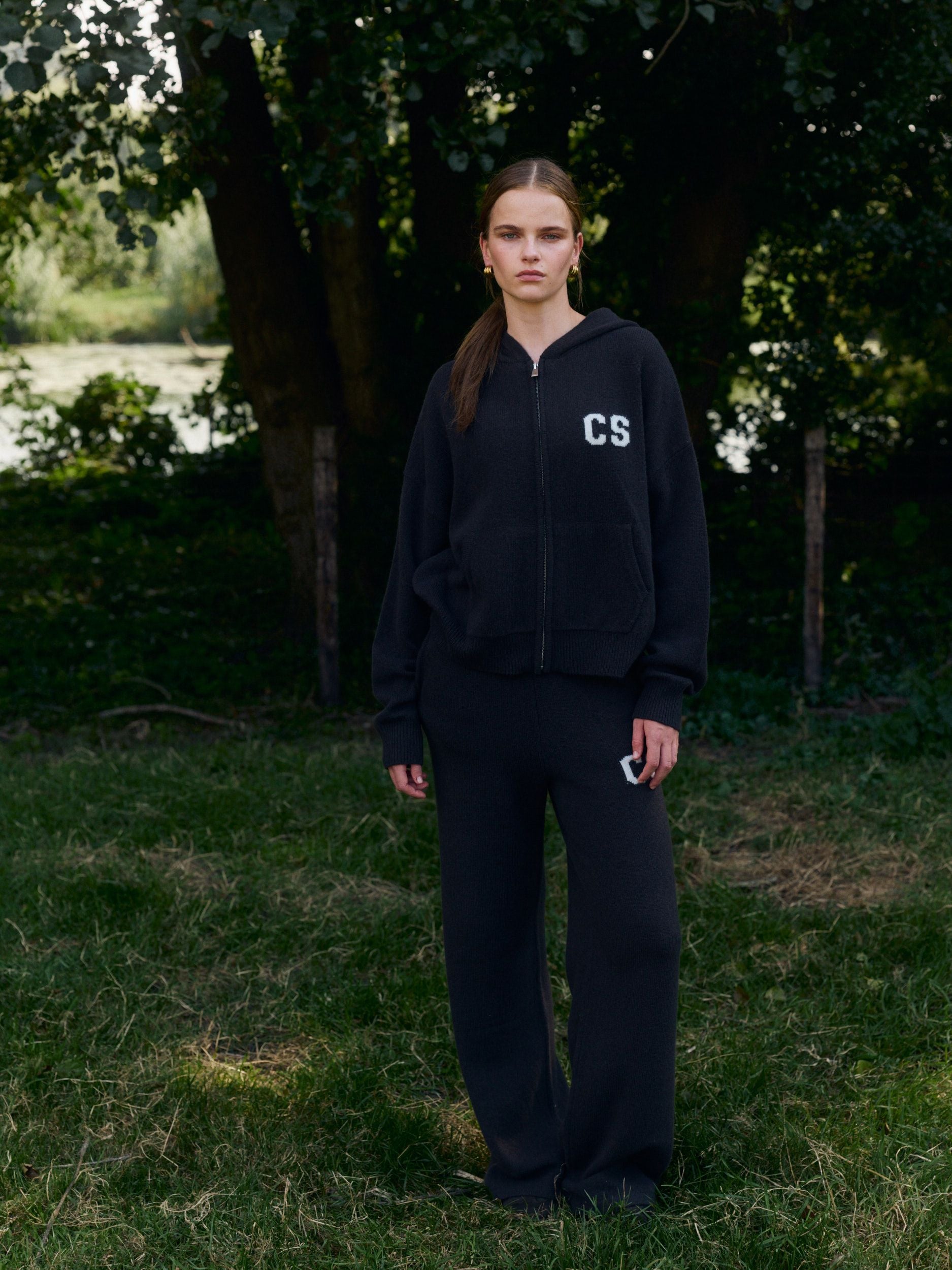 Woman wearing a cocoa bean woolknit zip jacket and matching straight-leg pants outdoors.