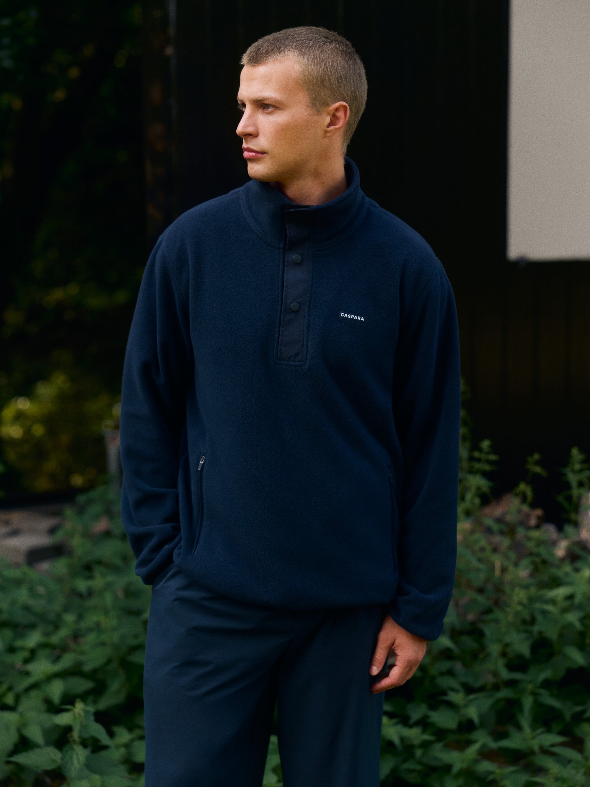 Man wearing a navy CASPARA polar fleece half-snap pullover outdoors.