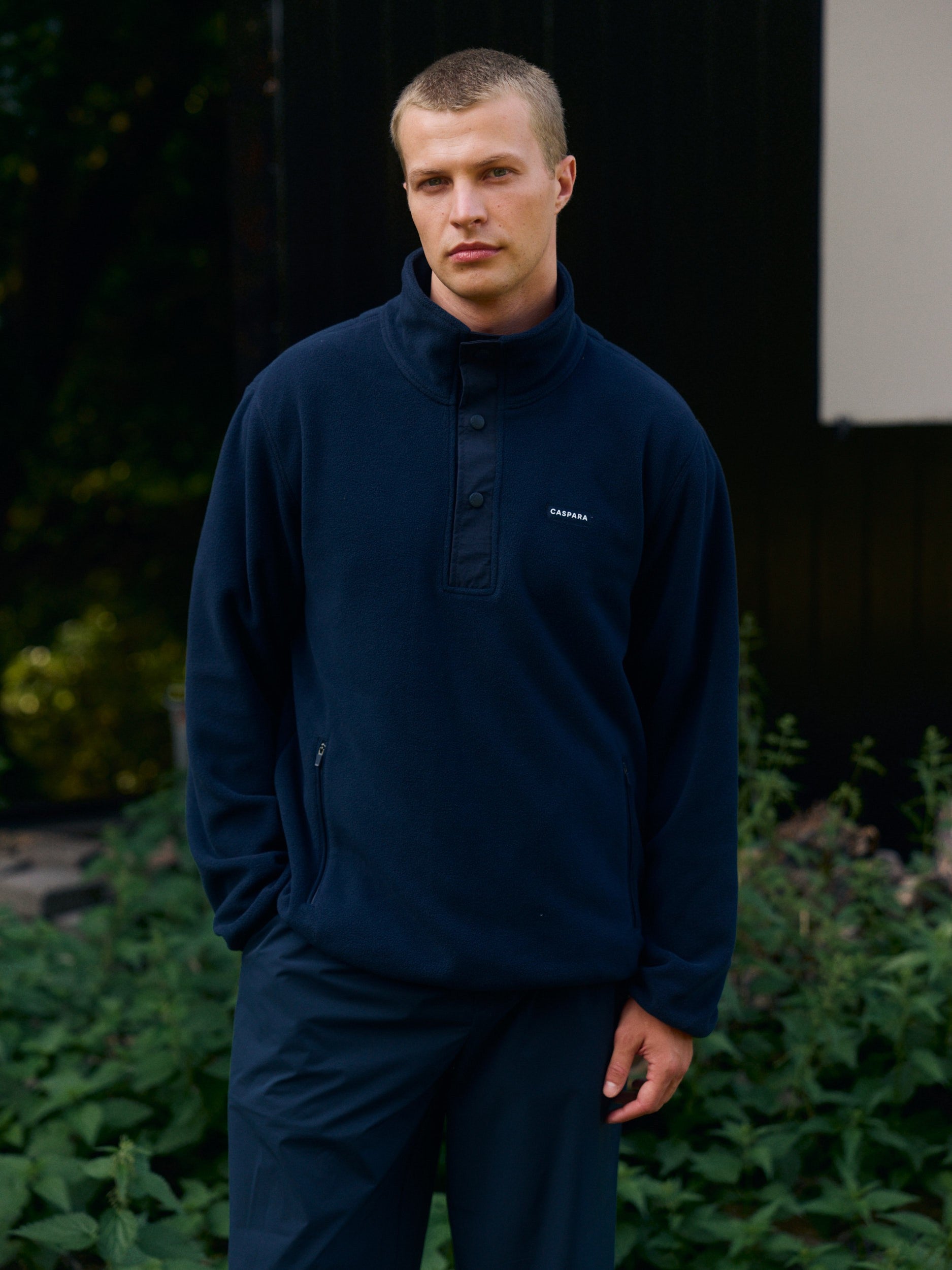 Man wearing a navy blue polar fleece half-snap pullover standing outdoors.