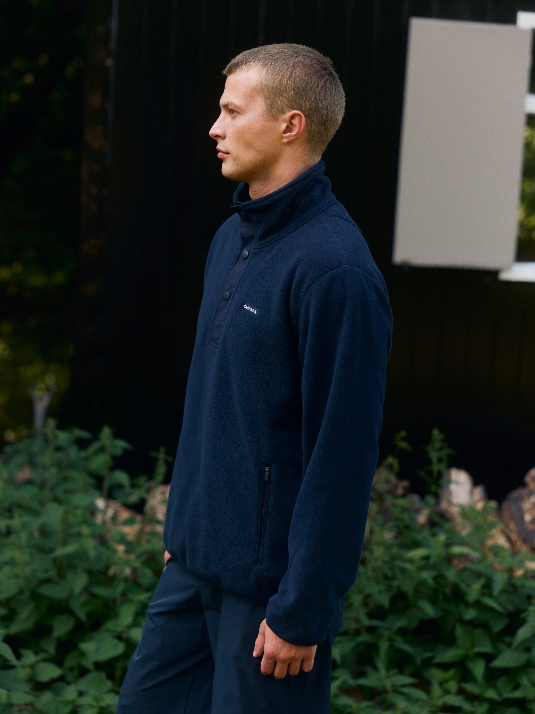 Man wearing a navy blue polar fleece half-snap pullover standing outdoors.