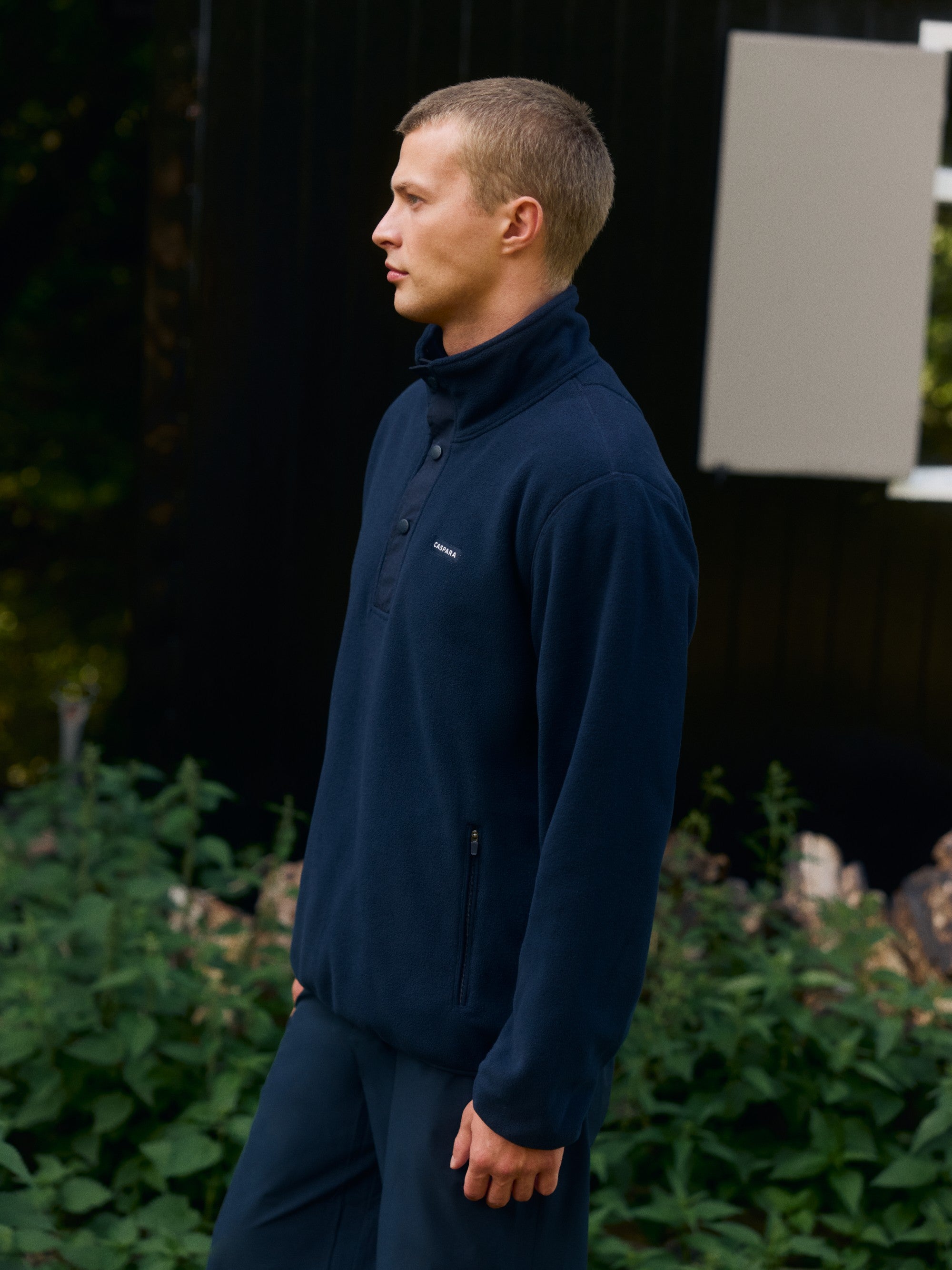 Man wearing a navy CASPARA polar fleece half-snap pullover outdoors.