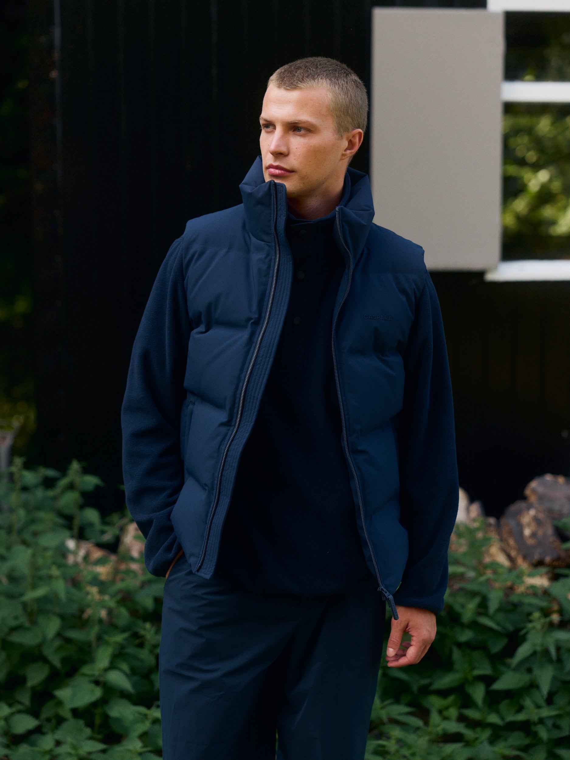 Man wearing a navy polar fleece half-snap pullover layered with a matching puffer vest.