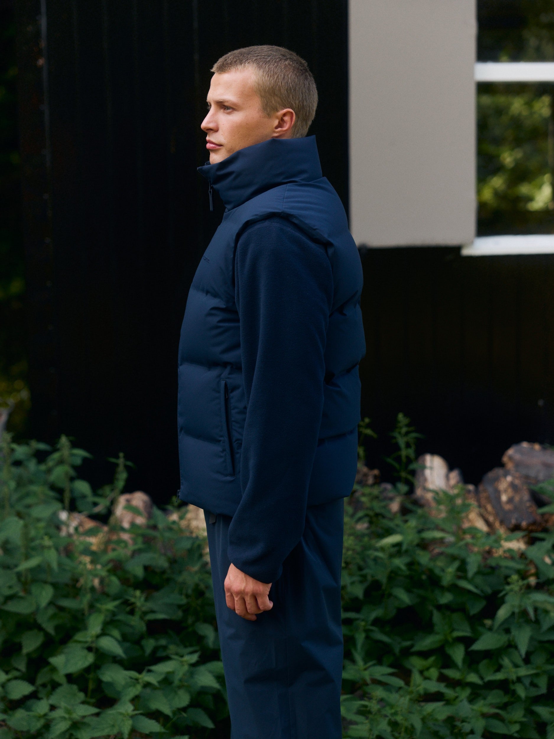 Man wearing a navy blue puffer vest layered over a matching fleece outdoors.