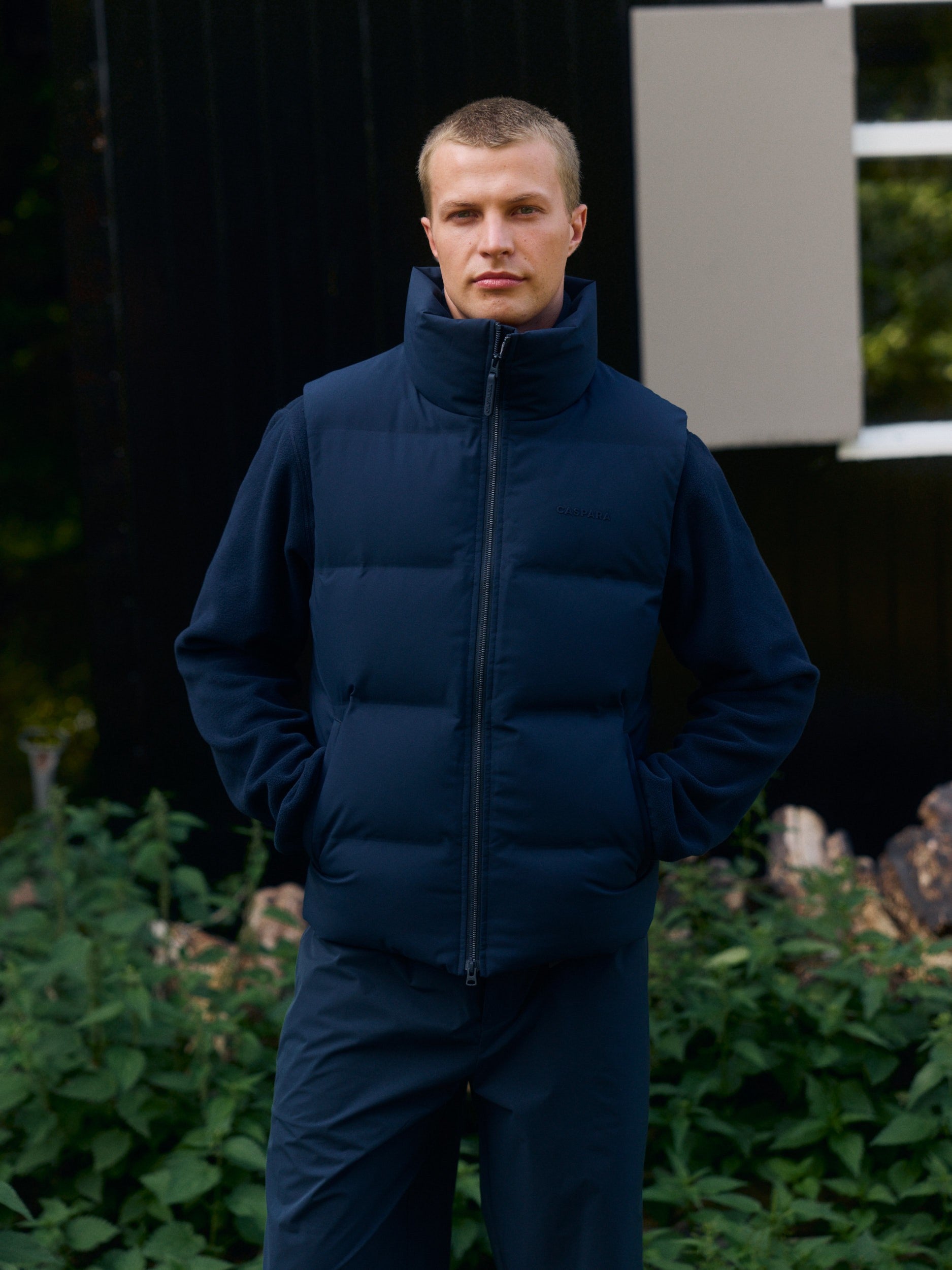 Man wearing a navy blue puffer vest layered over a fleece jacket outdoors.