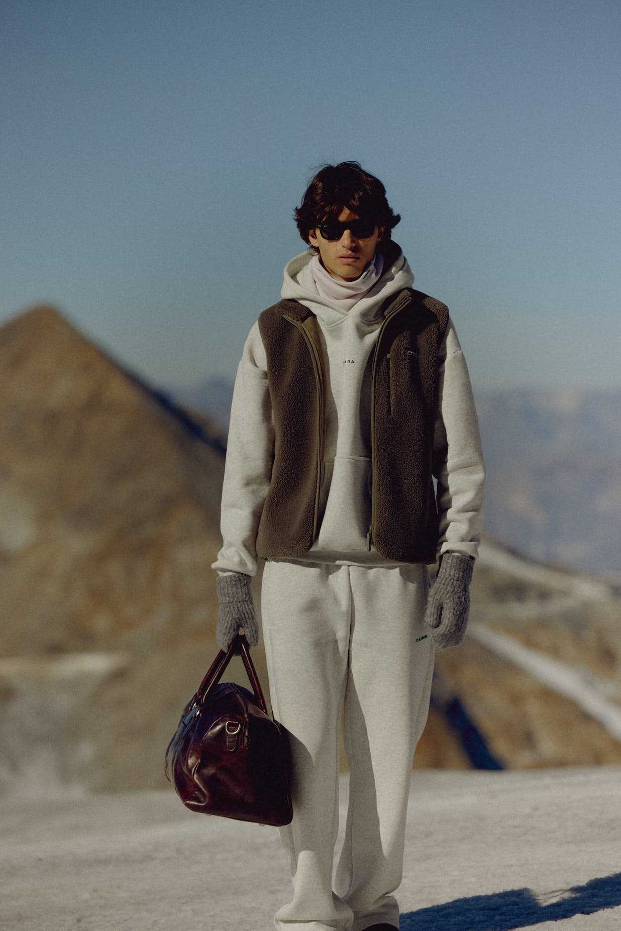 Man wearing a khaki CASPARA Cloudfleece vest in a mountain landscape.