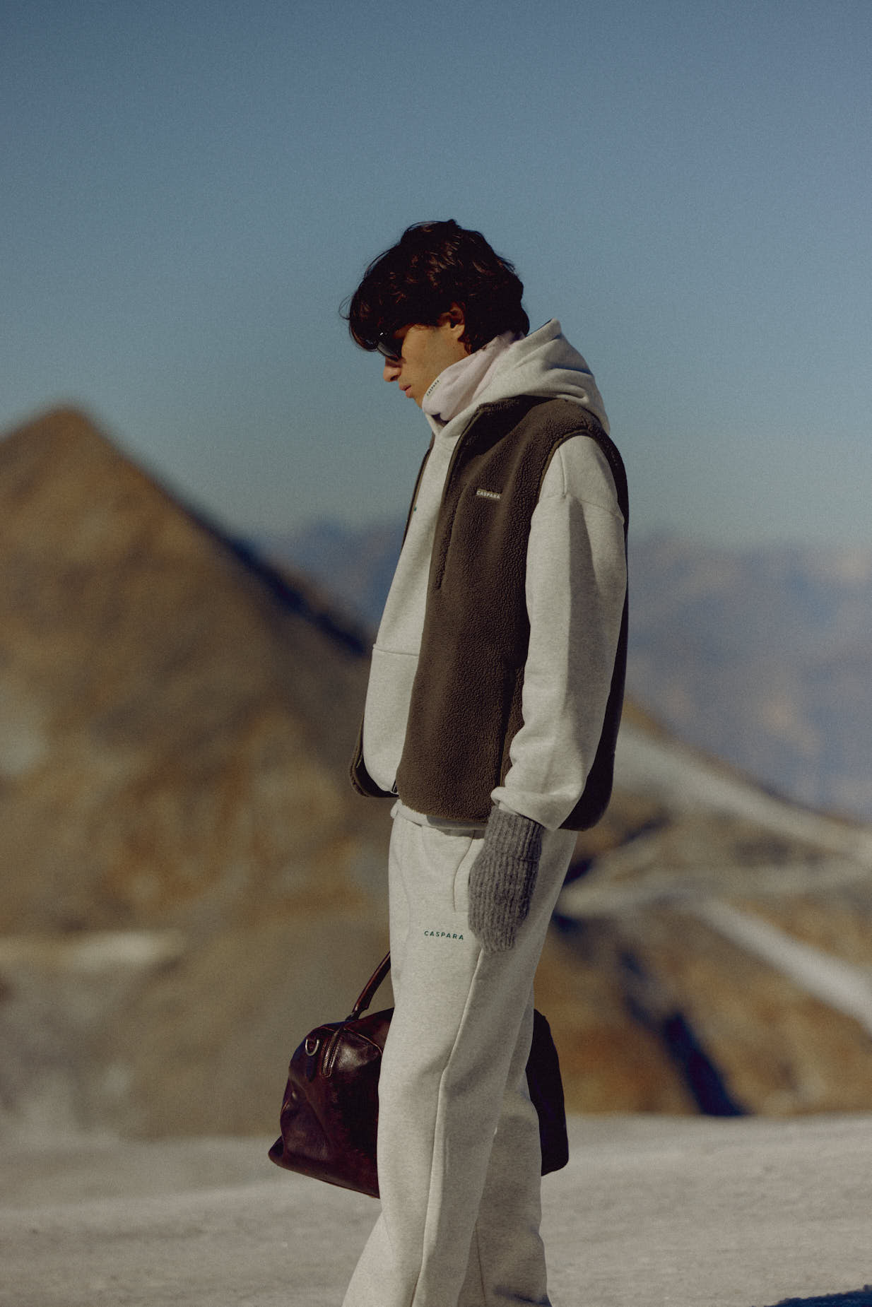 Man wearing a khaki CASPARA Cloudfleece vest in a mountain landscape.