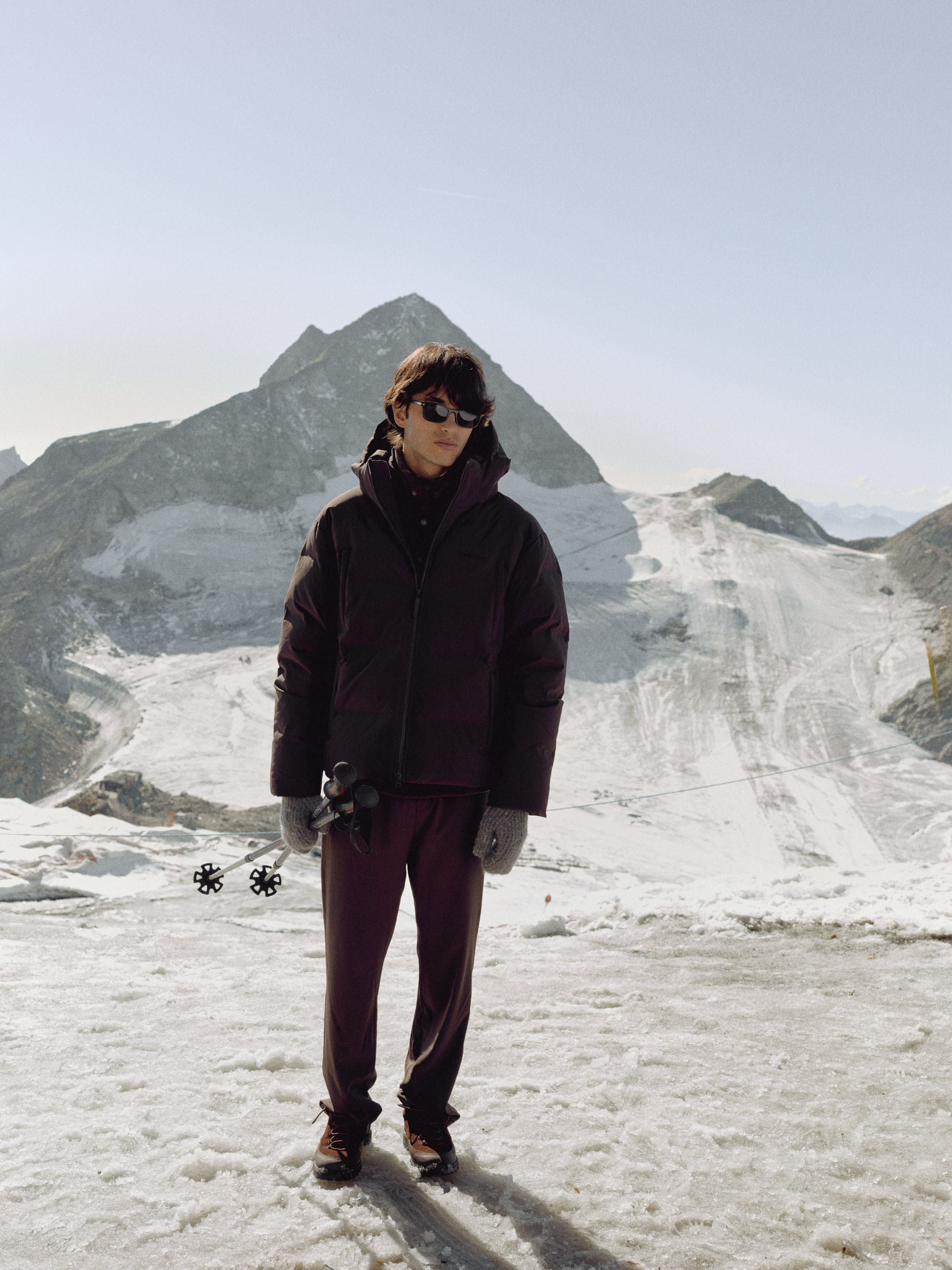 Man wearing a cocoa bean CASPARA Boreal puffer jacket on a snowy mountain.