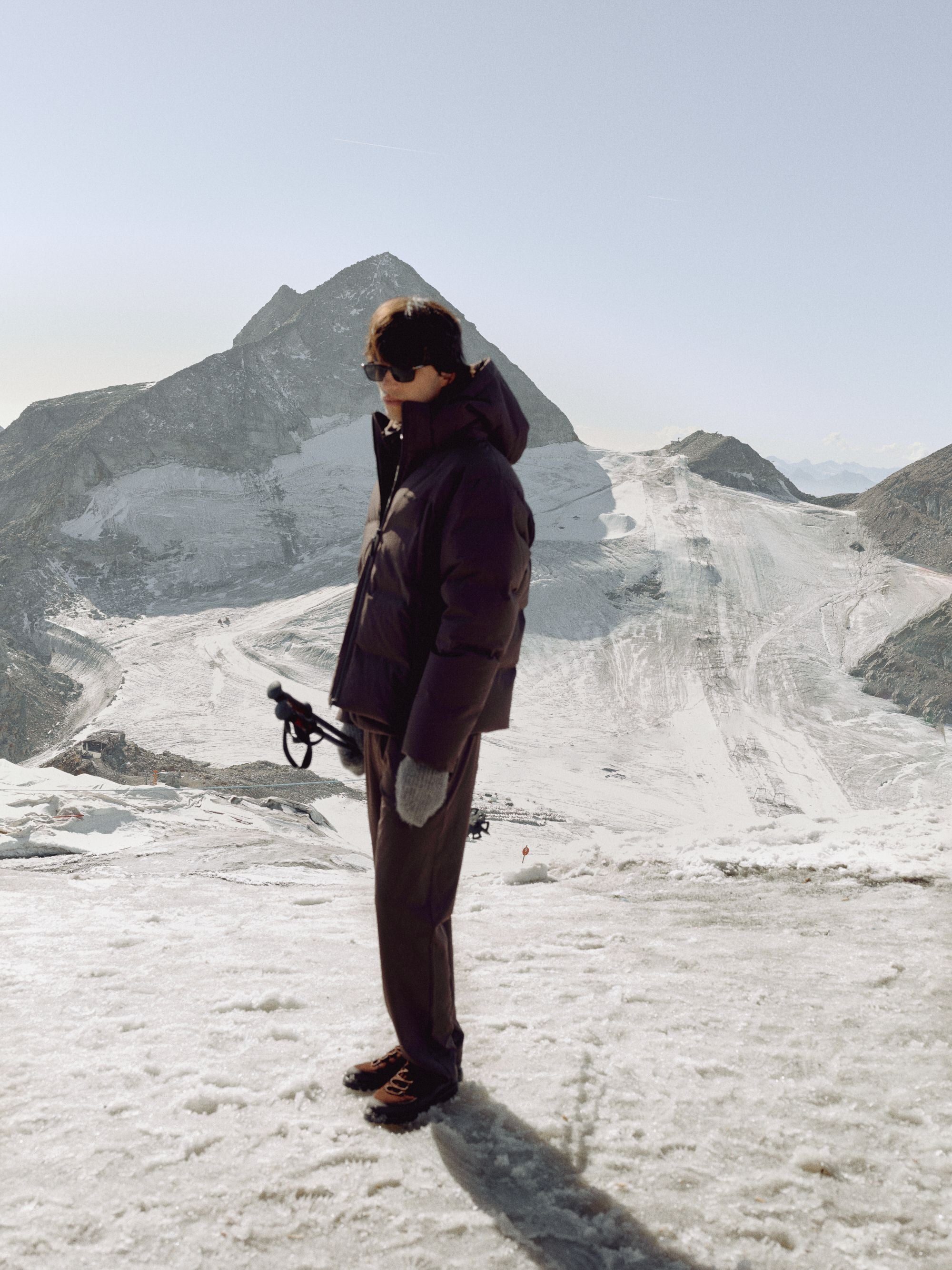 Man wearing a cocoa bean CASPARA Boreal puffer jacket on a snowy mountain.
