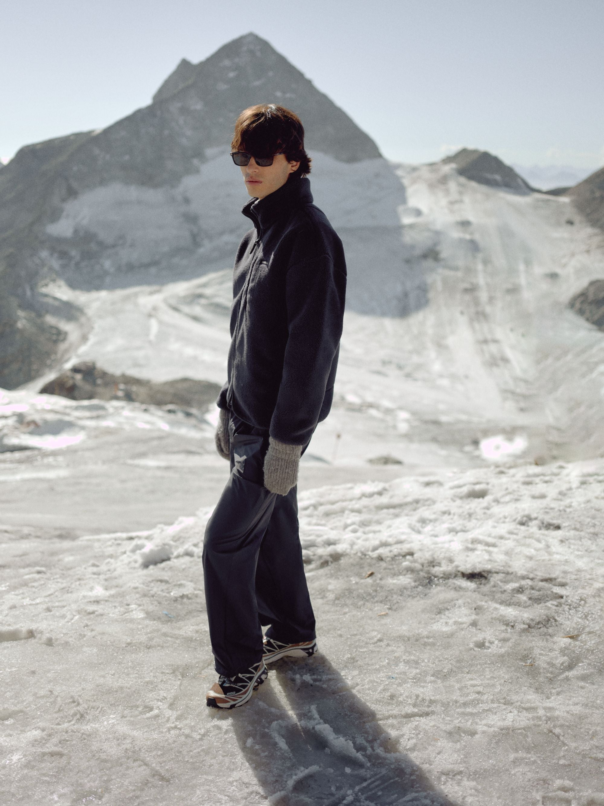 Man wearing a navy CASPARA Cloudfleece jacket standing on a snowy mountain.