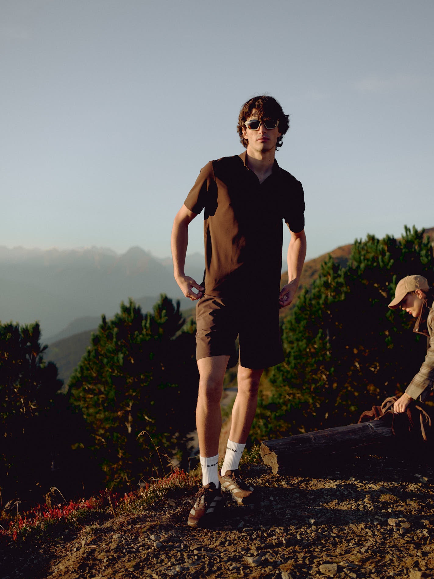 Man wearing an espresso CASPARA Vantage polo tee standing on a mountain hillside.