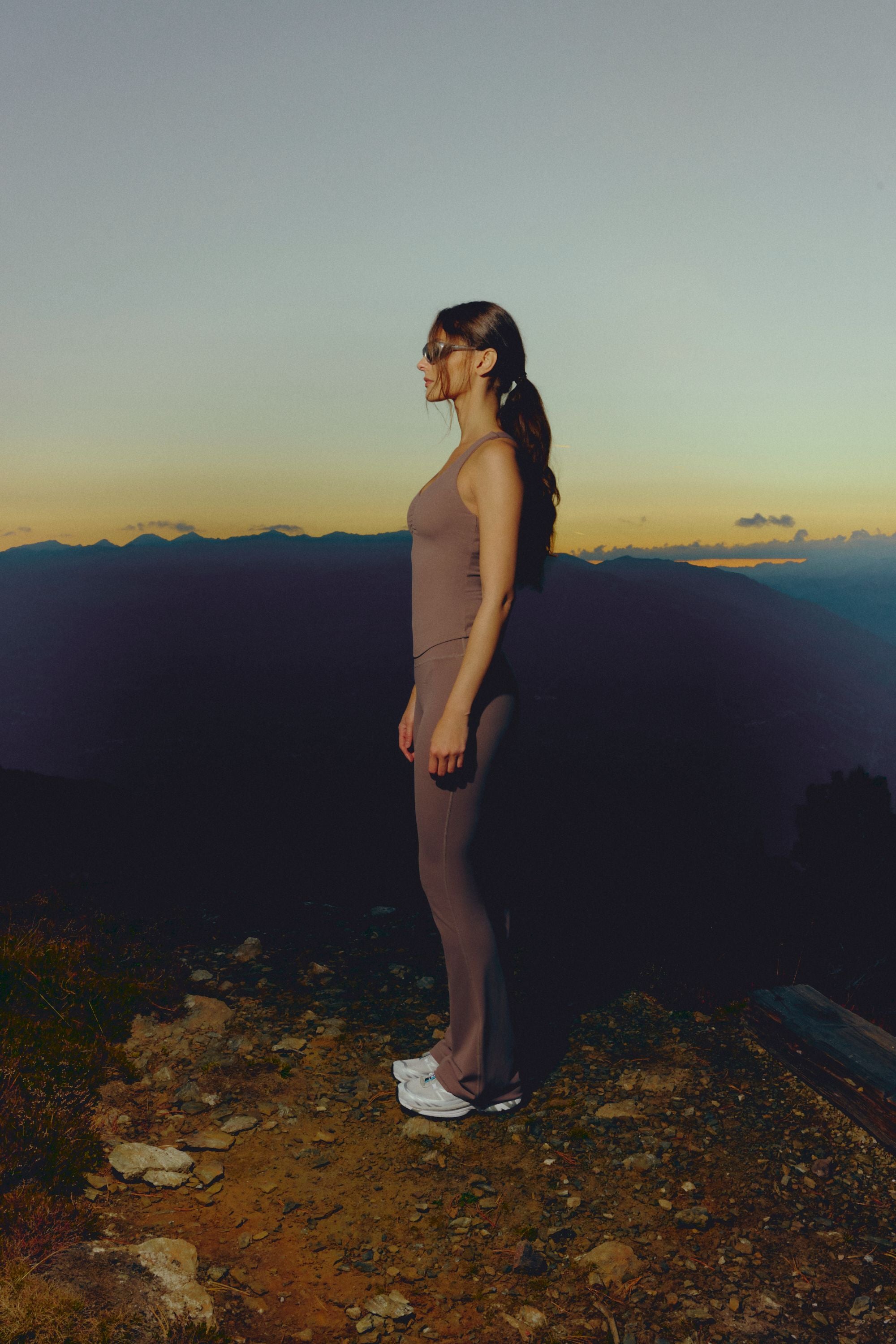 Woman wearing a walnut CASPARA Cloudform top and yoga pants in the mountains.