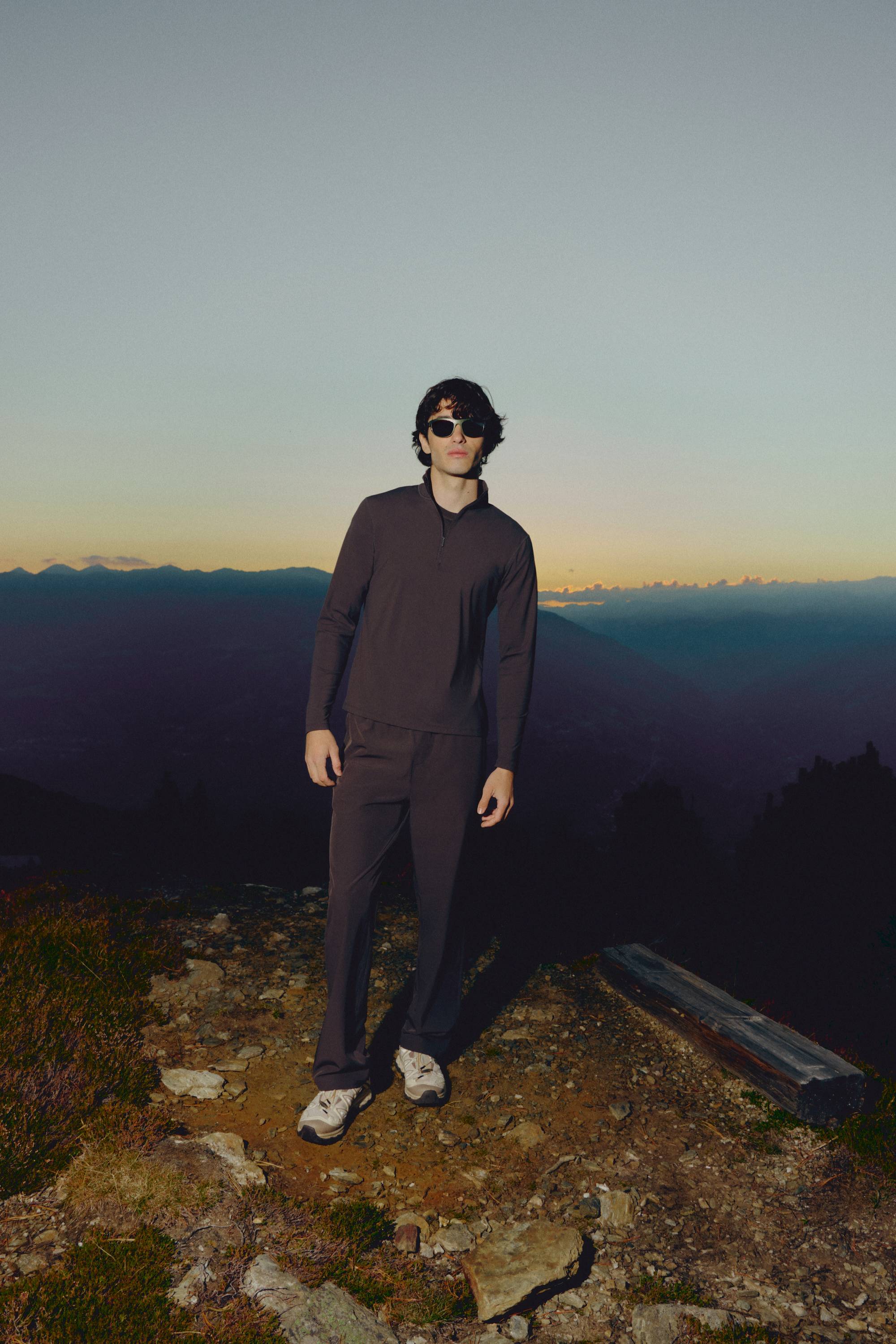 Man wearing an espresso CASPARA Prime Core half zip in a mountain landscape.