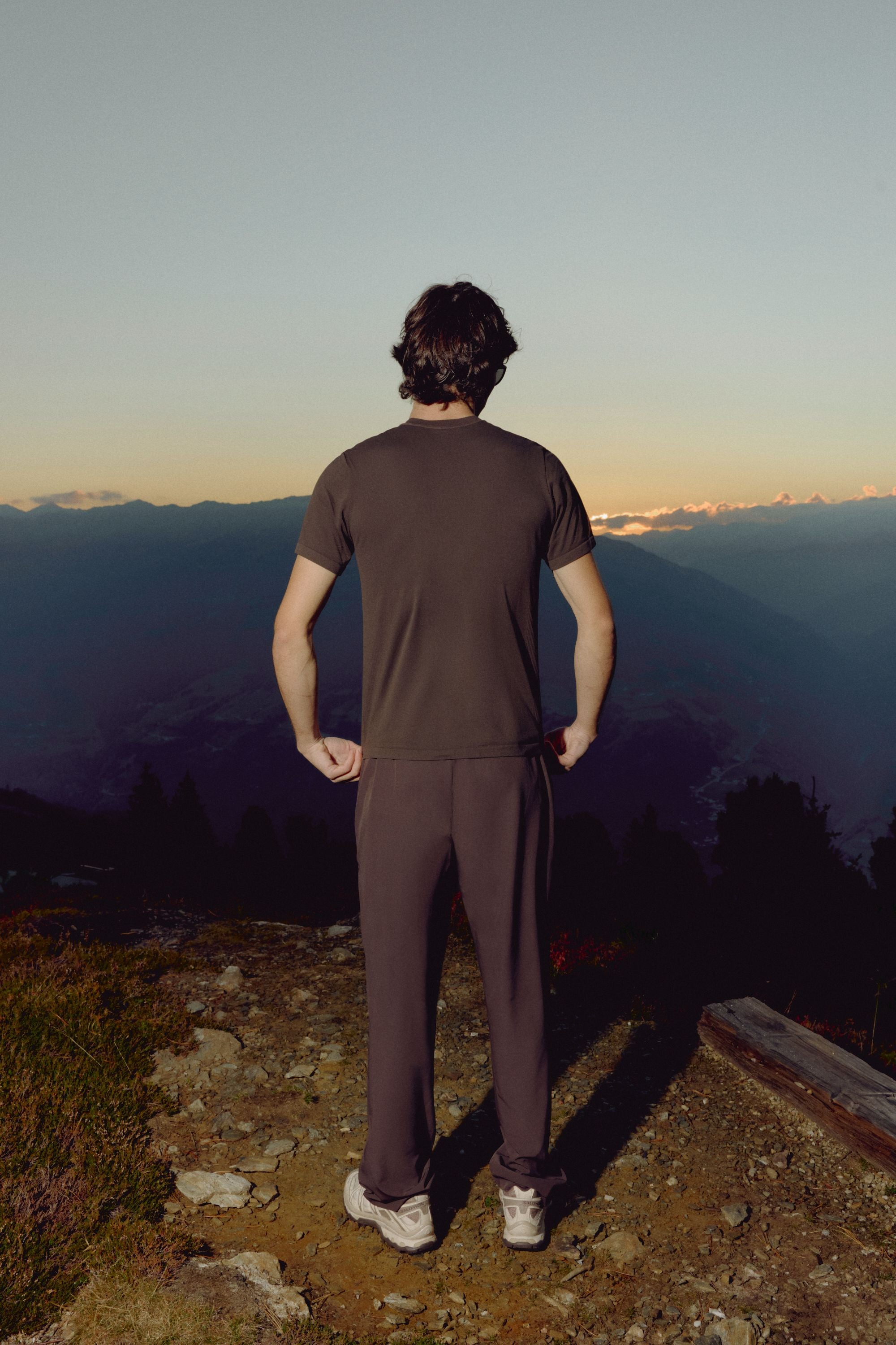 Back view of a man wearing an espresso CASPARA Seamlite t-shirt overlooking mountains.