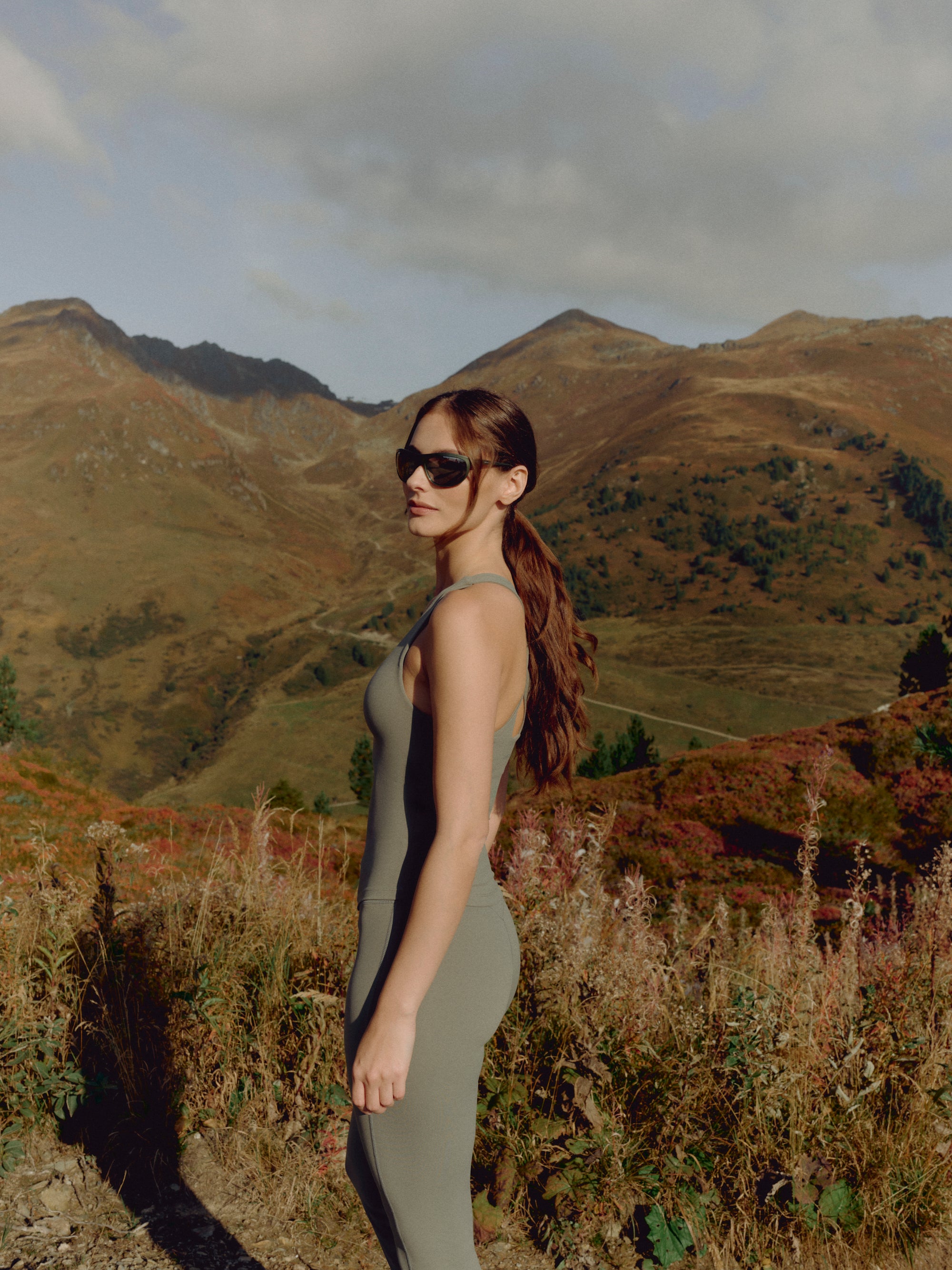 Woman wearing a khaki CASPARA Cloudform scrunch top in a mountain landscape.