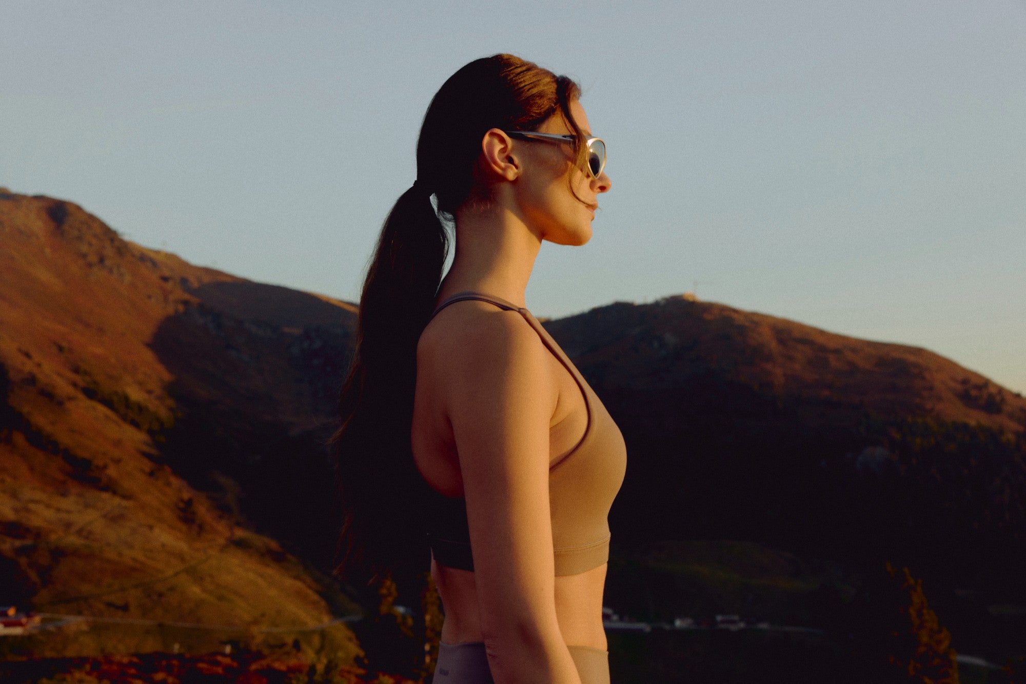 Woman wearing a walnut CASPARA Cloudform sports bra in a mountain landscape.