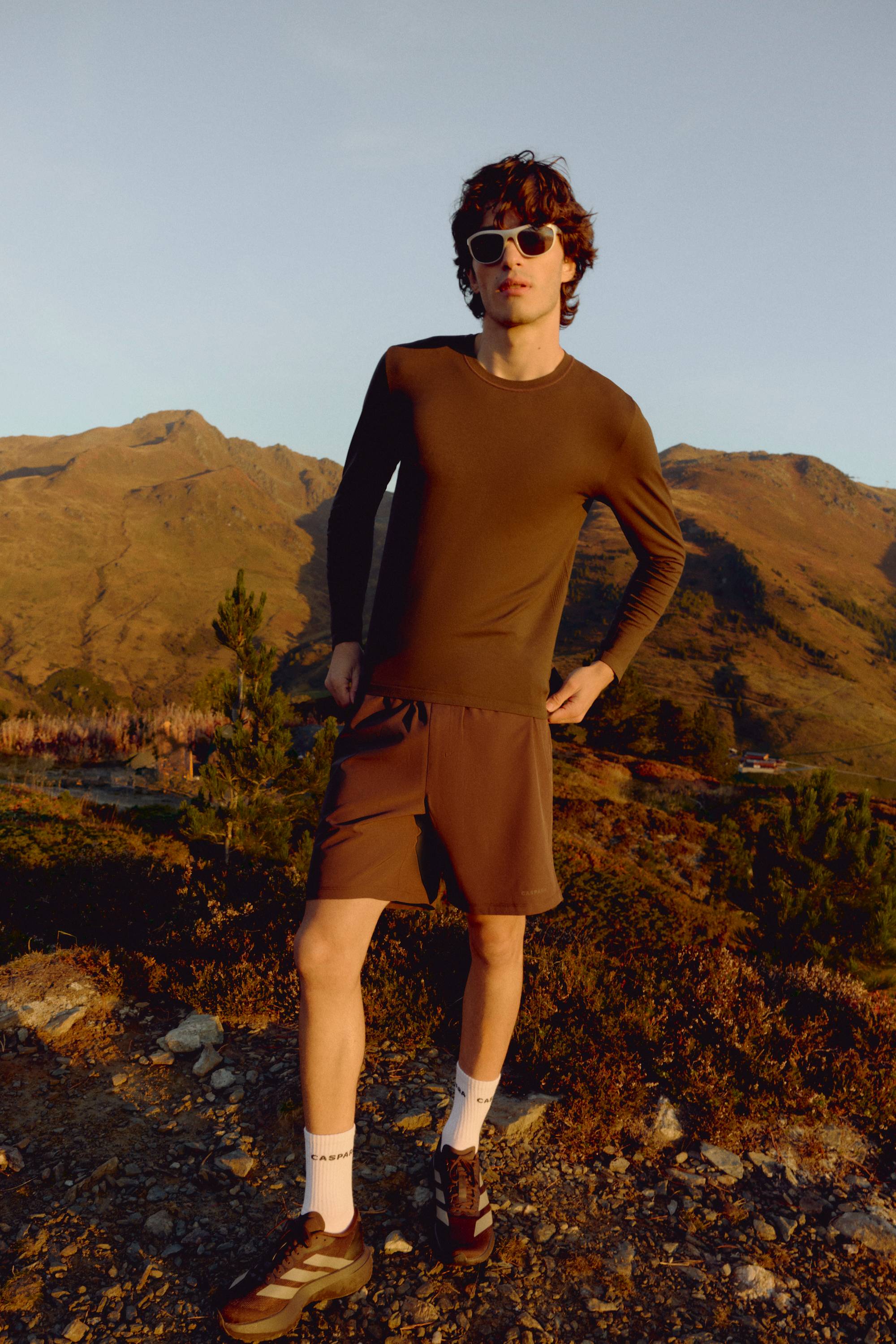 Man wearing an espresso CASPARA Seamlite long sleeve shirt in a mountain landscape.