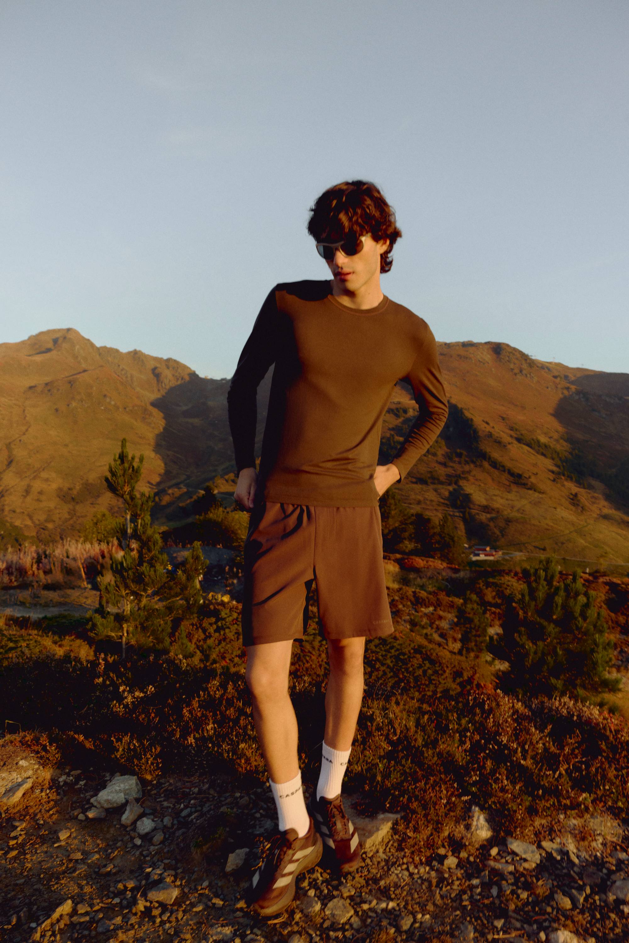 Man wearing an espresso CASPARA Seamlite long sleeve shirt on a mountain ridge.