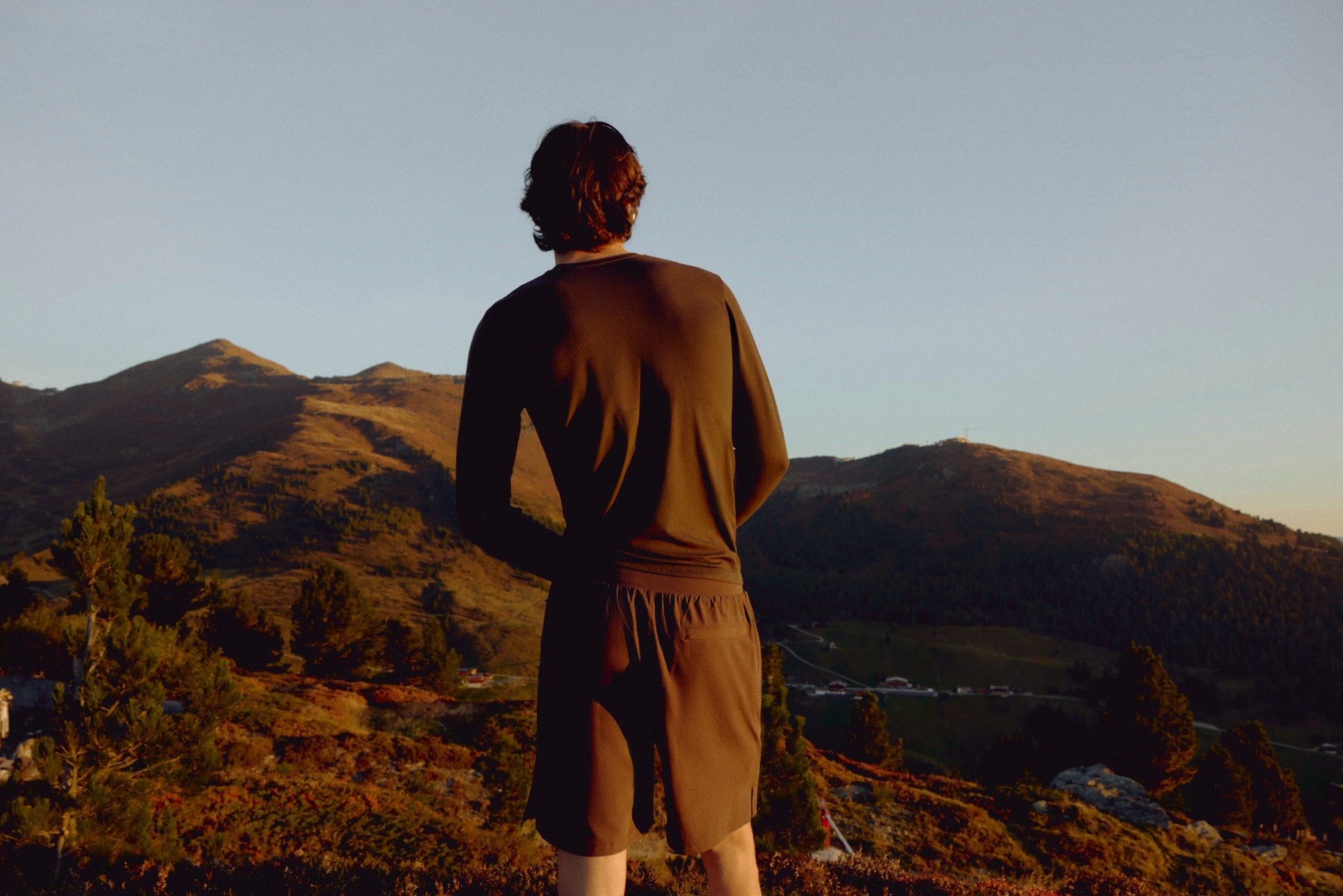 Man wearing an espresso CASPARA Seamlite long sleeve shirt overlooking mountains.