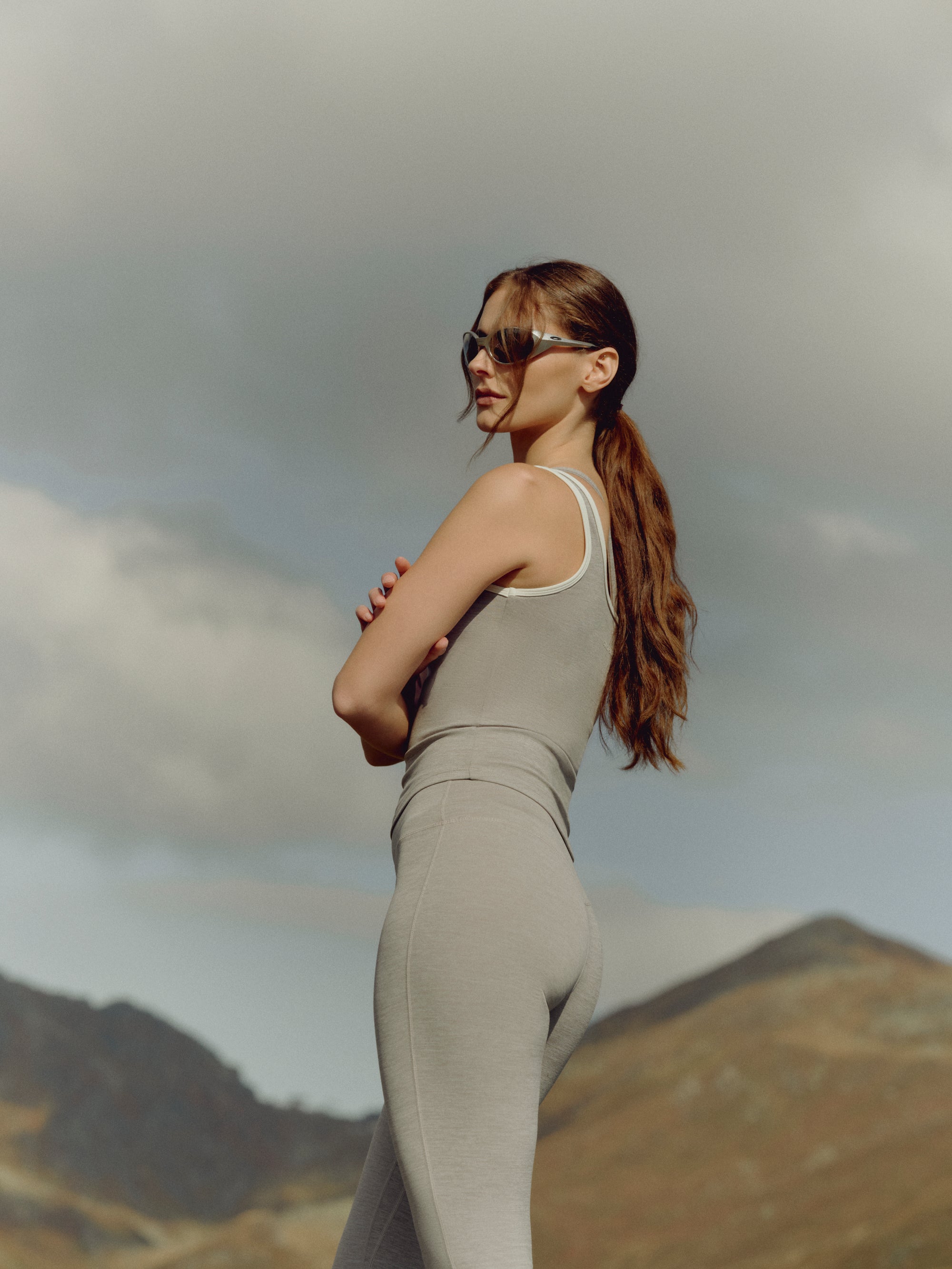 Woman wearing a grey melange CASPARA Cloudform square neck top against a mountain backdrop.