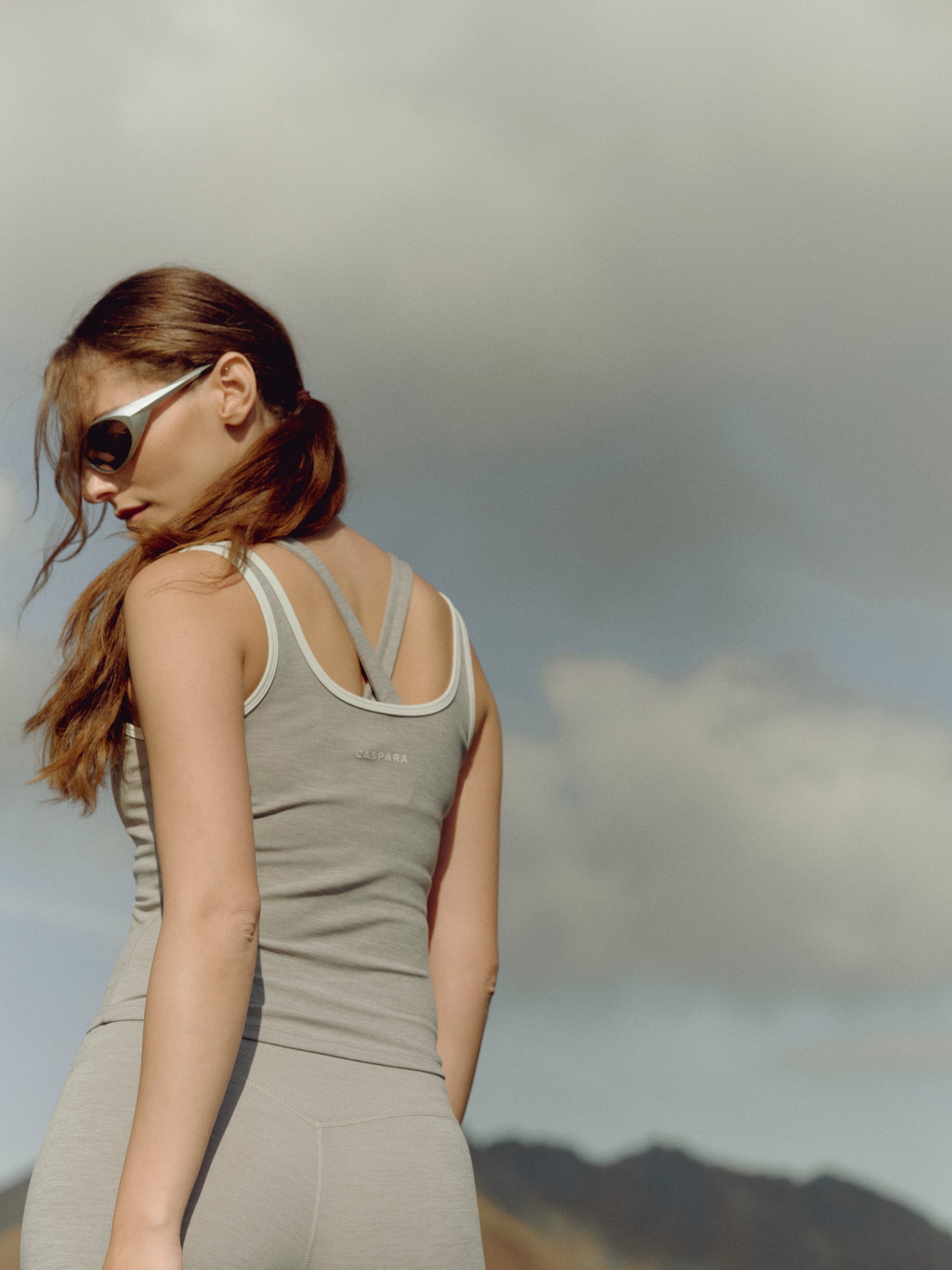 Woman wearing a grey melange CASPARA Cloudform square neck top outdoors against an open sky.