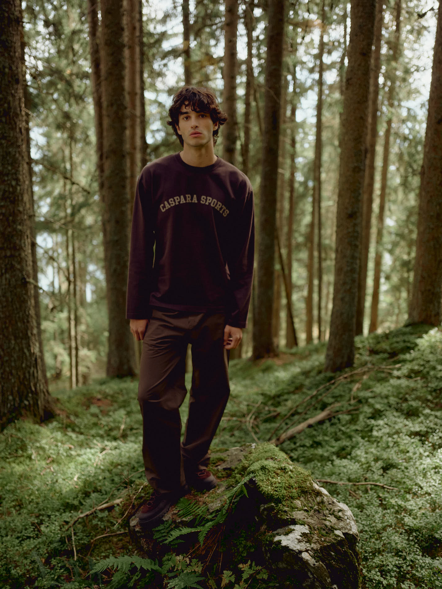 Man wearing an espresso CASPARA CS Signature long sleeve shirt standing in a forest.