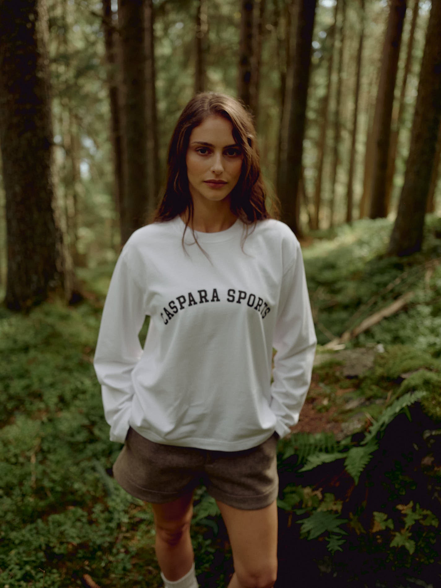 Woman wearing a white CASPARA CS Signature long sleeve shirt in a forest.