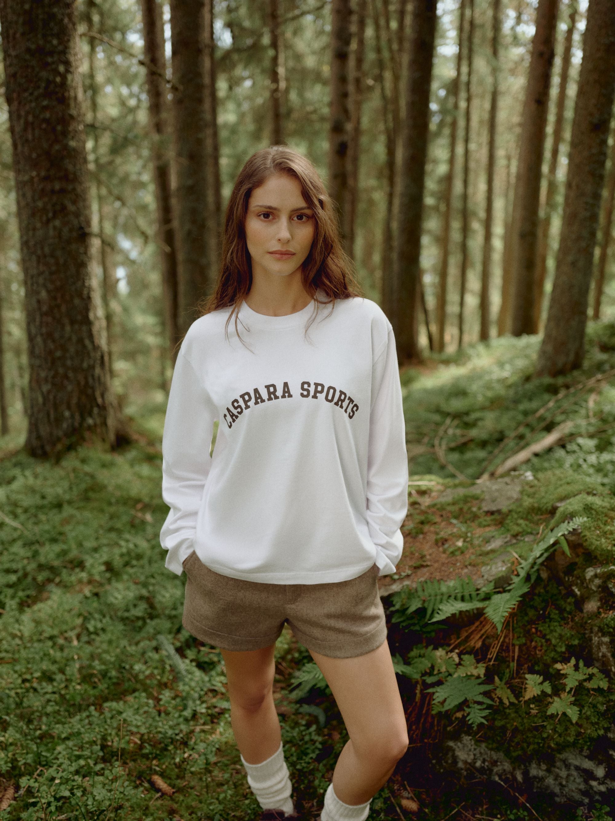 Woman wearing a white CASPARA CS Signature long sleeve shirt in a forest.