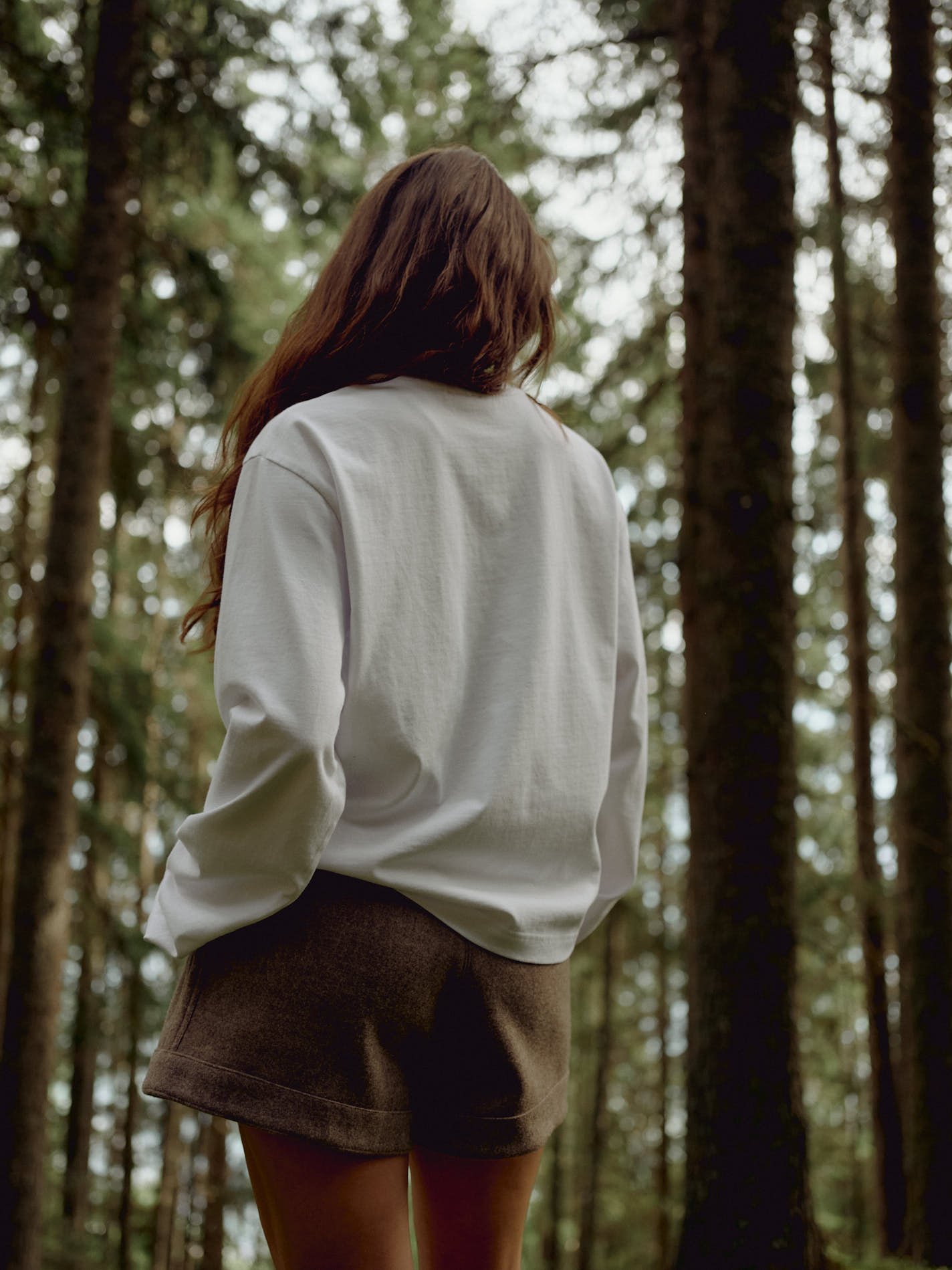 Woman wearing a white CASPARA CS Signature long sleeve shirt in a forest.