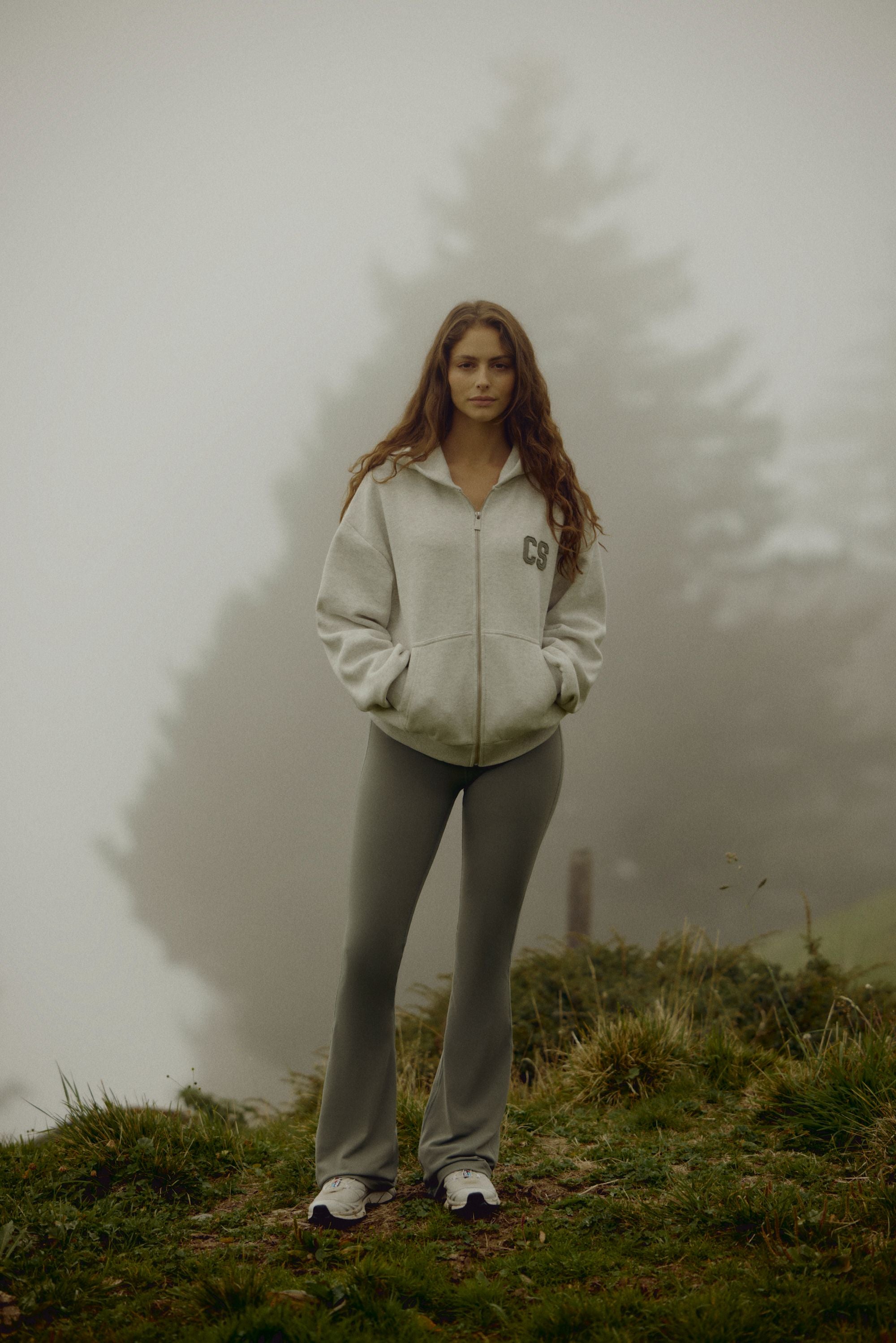 Woman wearing a grey melange CASPARA CS zip hoodie standing on a foggy hillside.