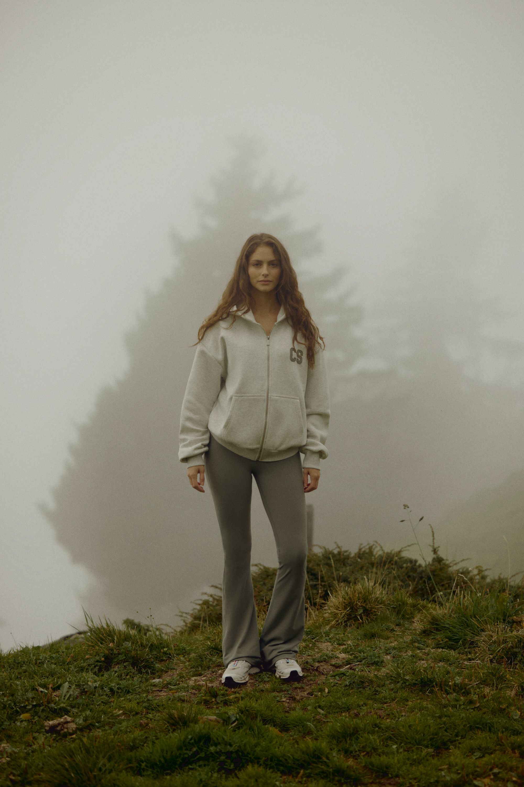 Woman wearing a grey melange CASPARA CS zip hoodie on a foggy hillside.