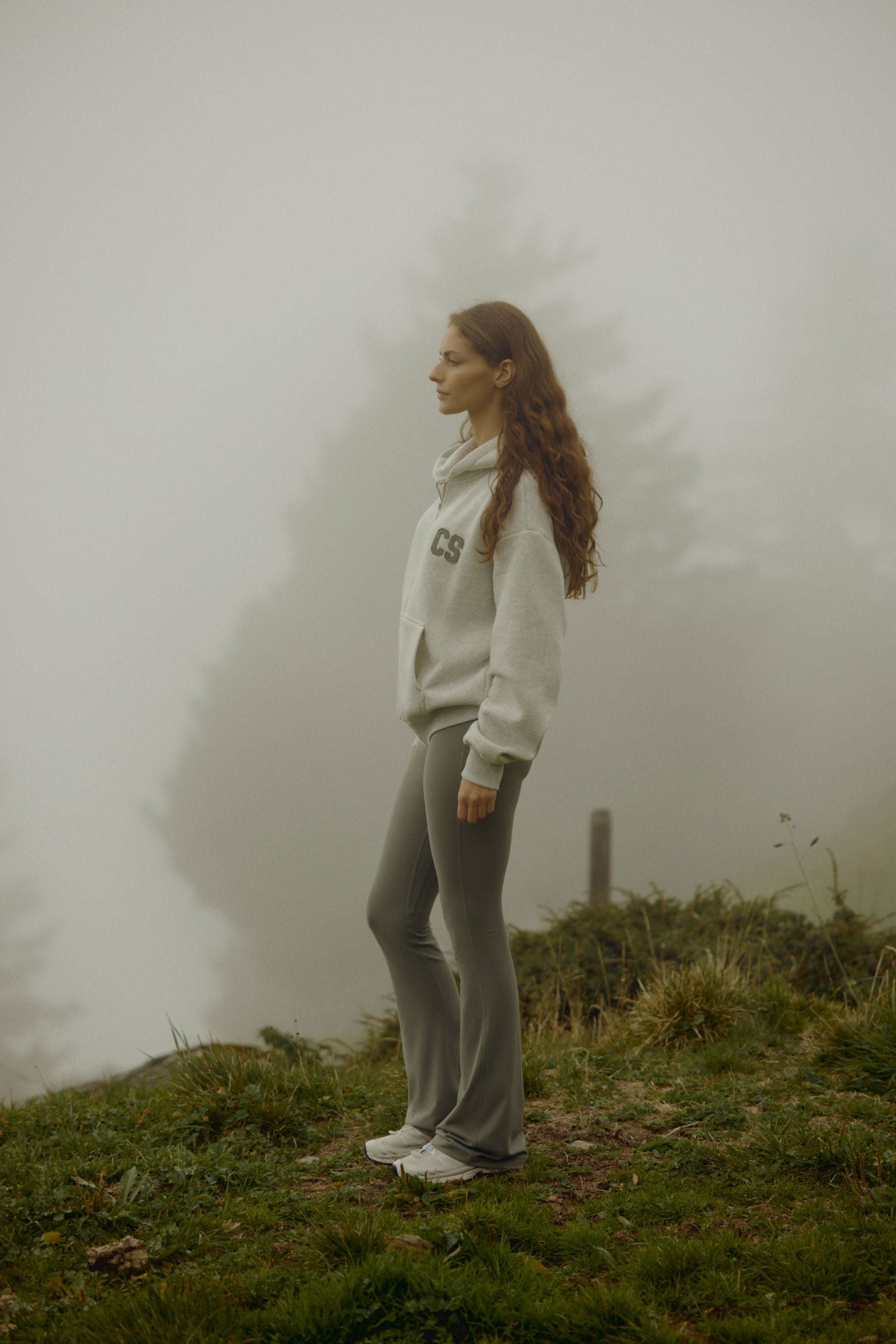 Woman wearing a grey melange CASPARA CS zip hoodie standing on a foggy hillside.