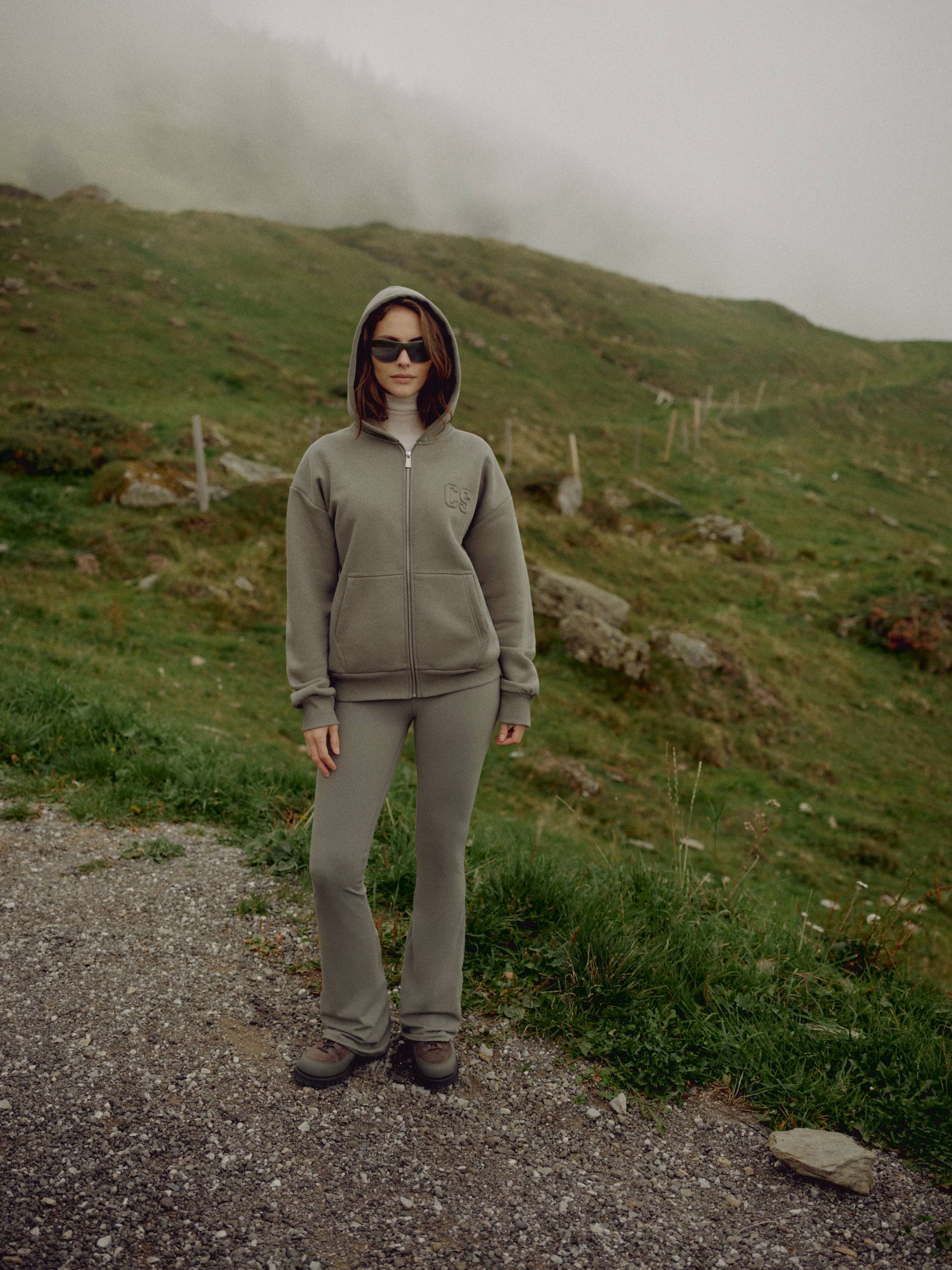 Woman wearing a khaki CASPARA CS zip hoodie and matching pants on a misty hillside.