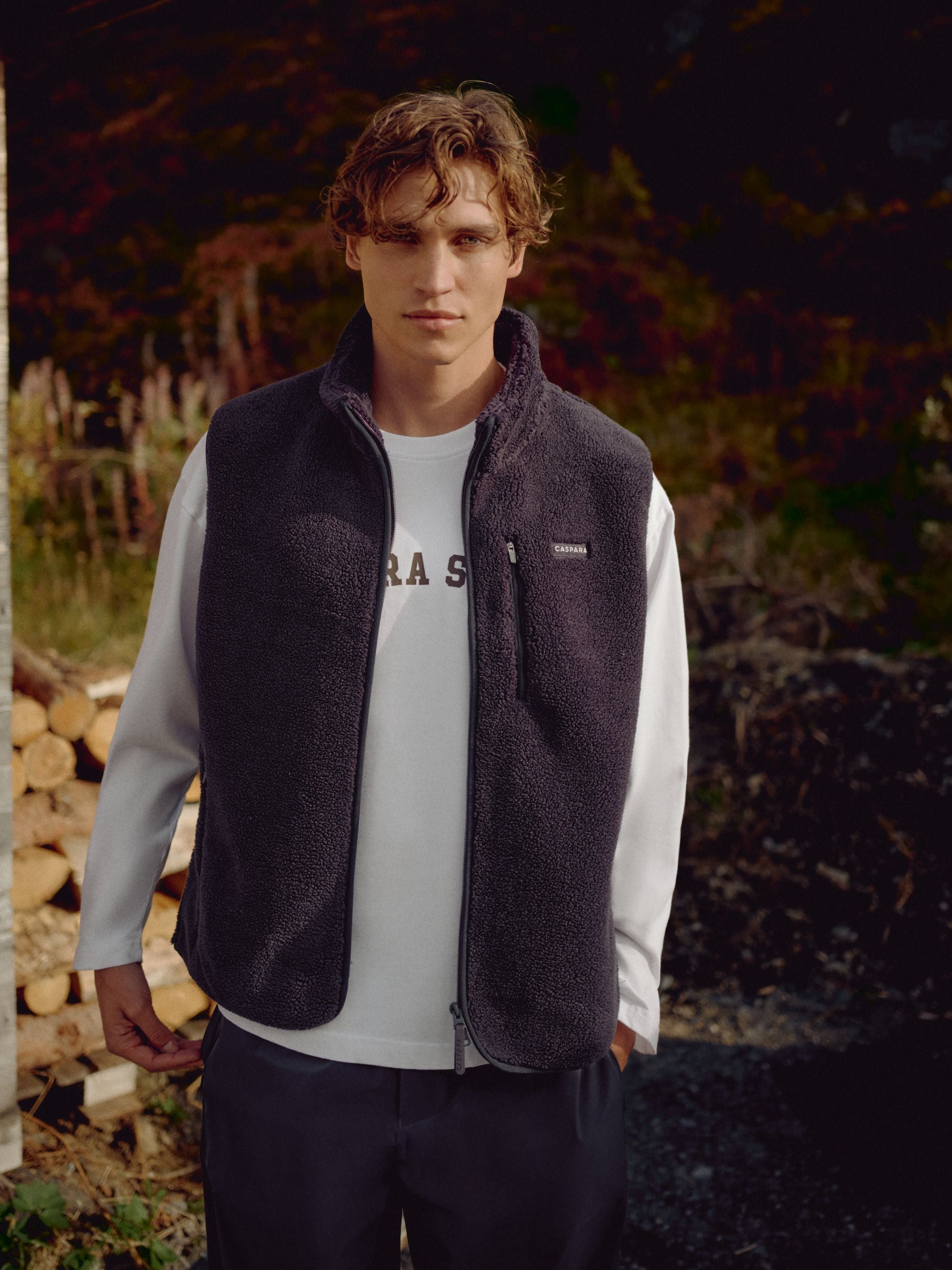 Man wearing a navy CASPARA Cloudfleece vest layered over a white long-sleeve shirt.