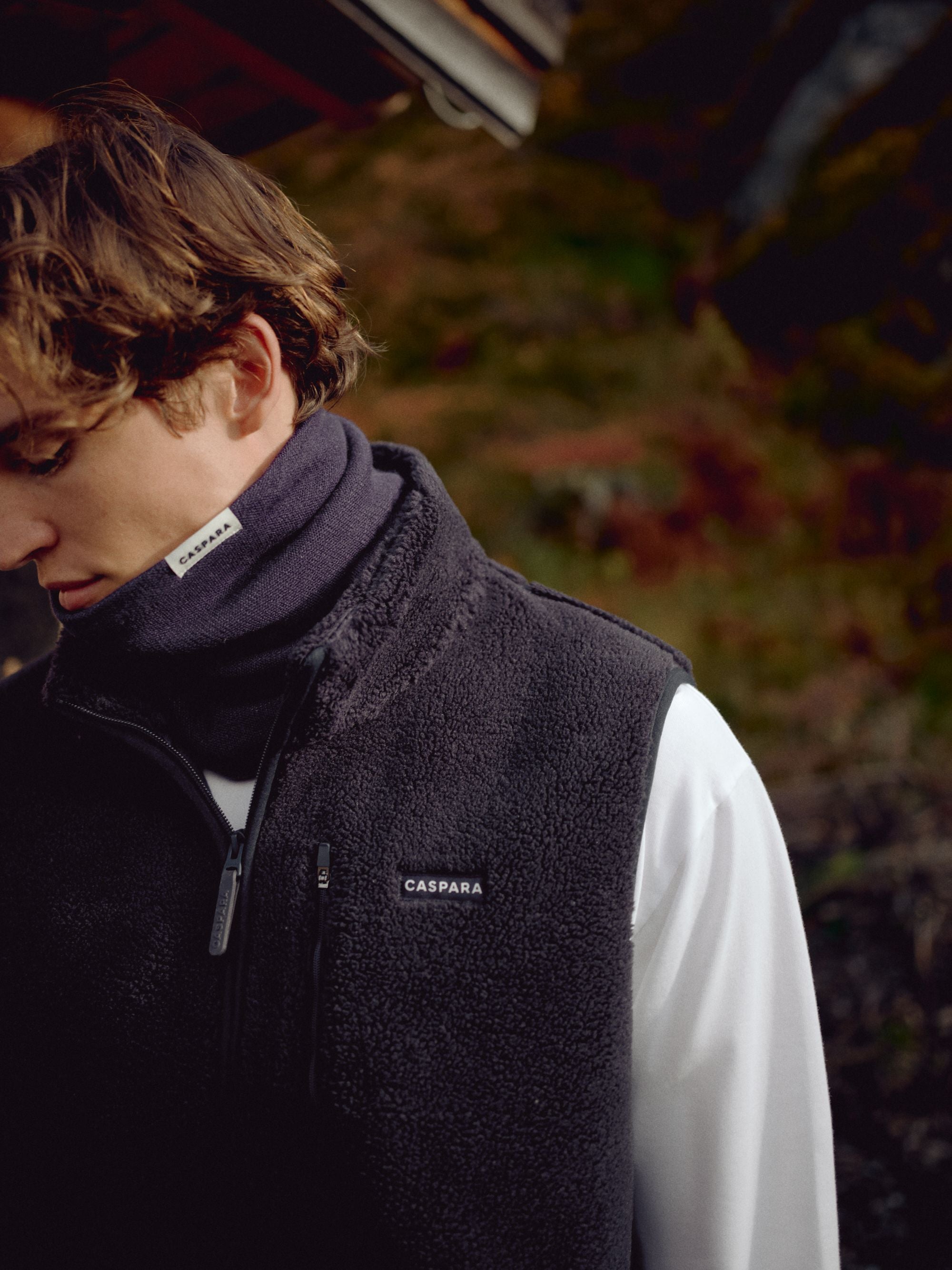 Man wearing a navy CASPARA Classic Neckwarmer outdoors with a fleece vest.