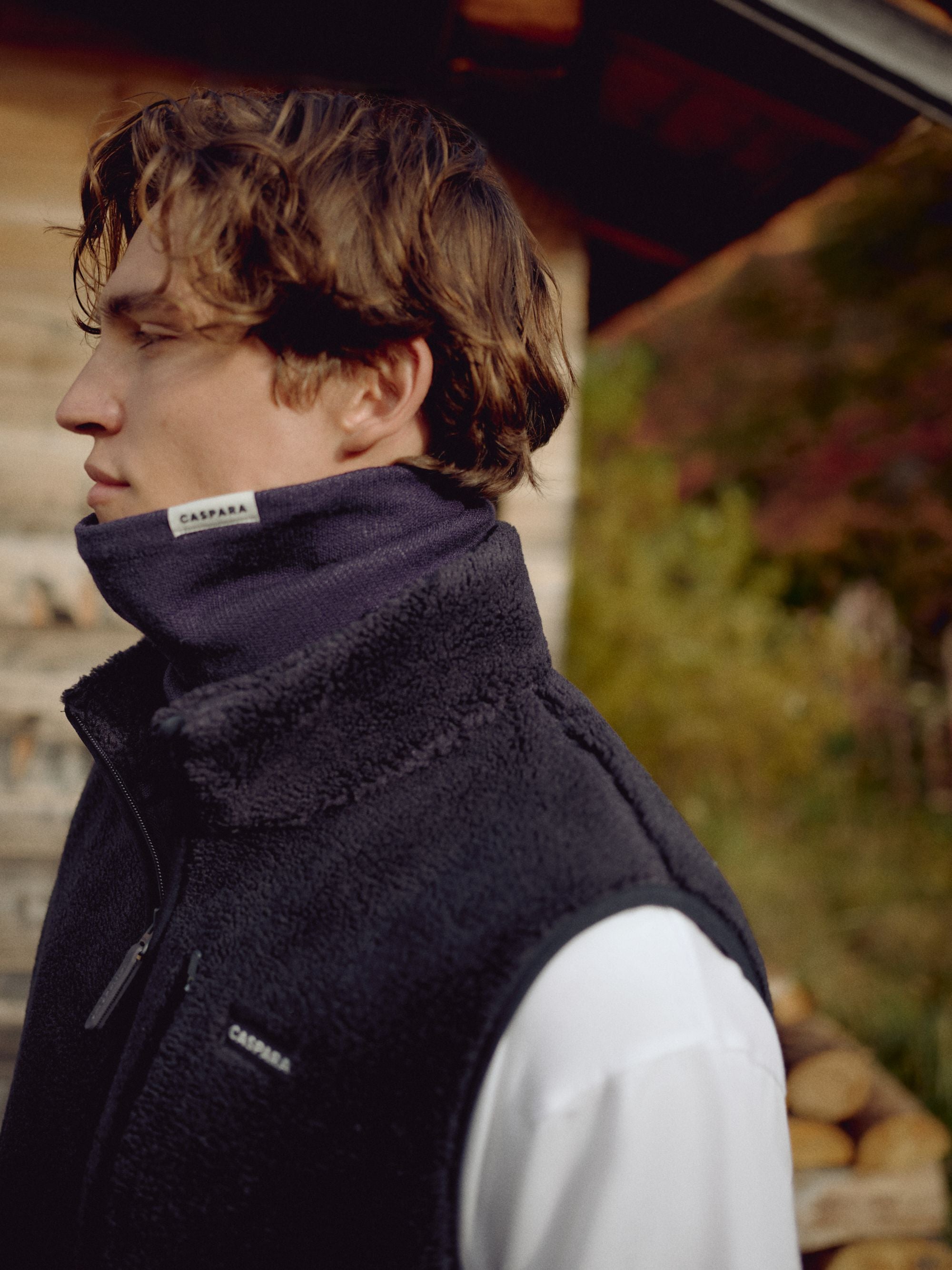 Man wearing a navy CASPARA Classic Neckwarmer and fleece vest outdoors.