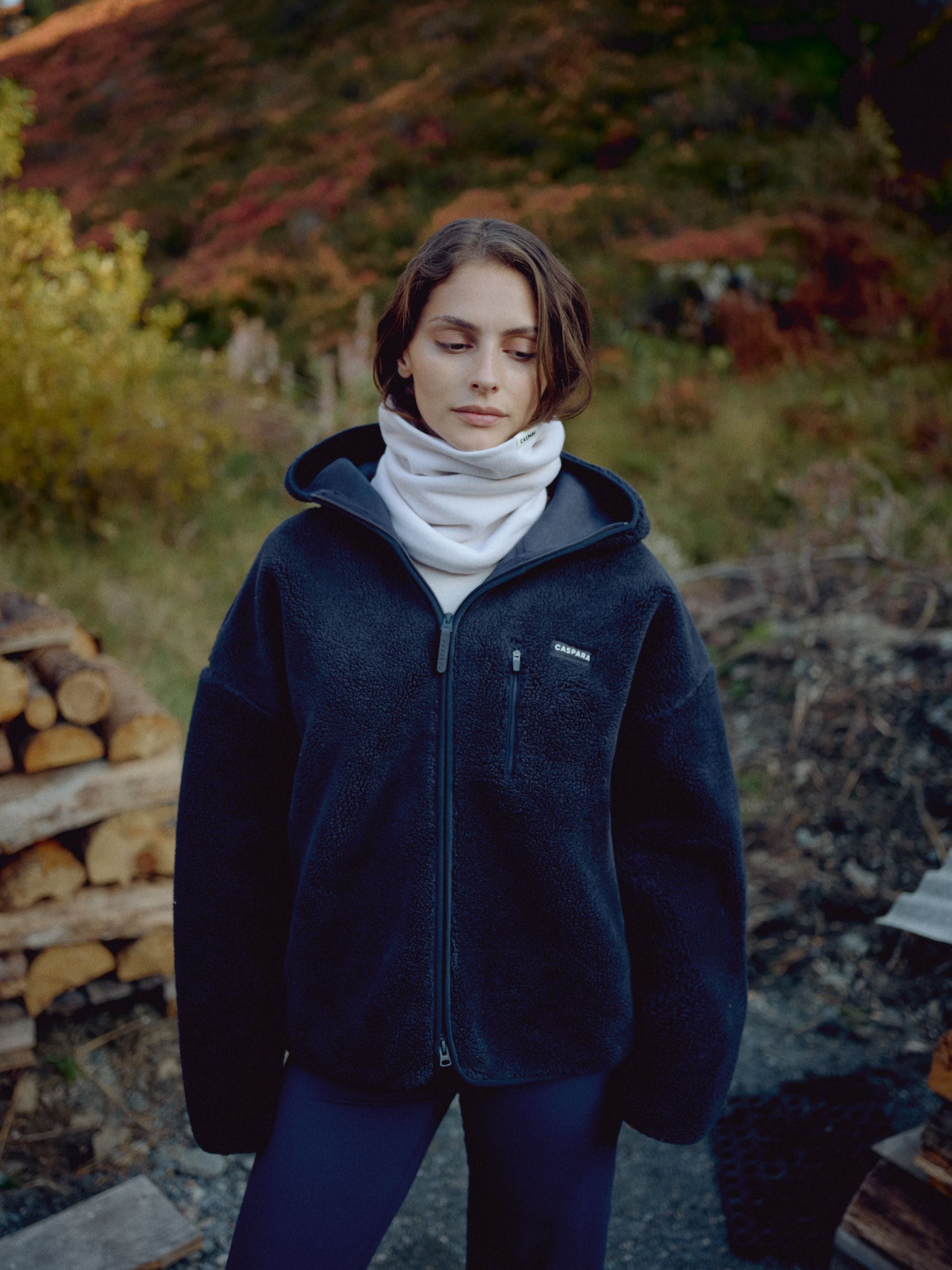 Woman outdoors wearing the CASPARA Classic Neckwarmer in creme and a dark fleece jacket.