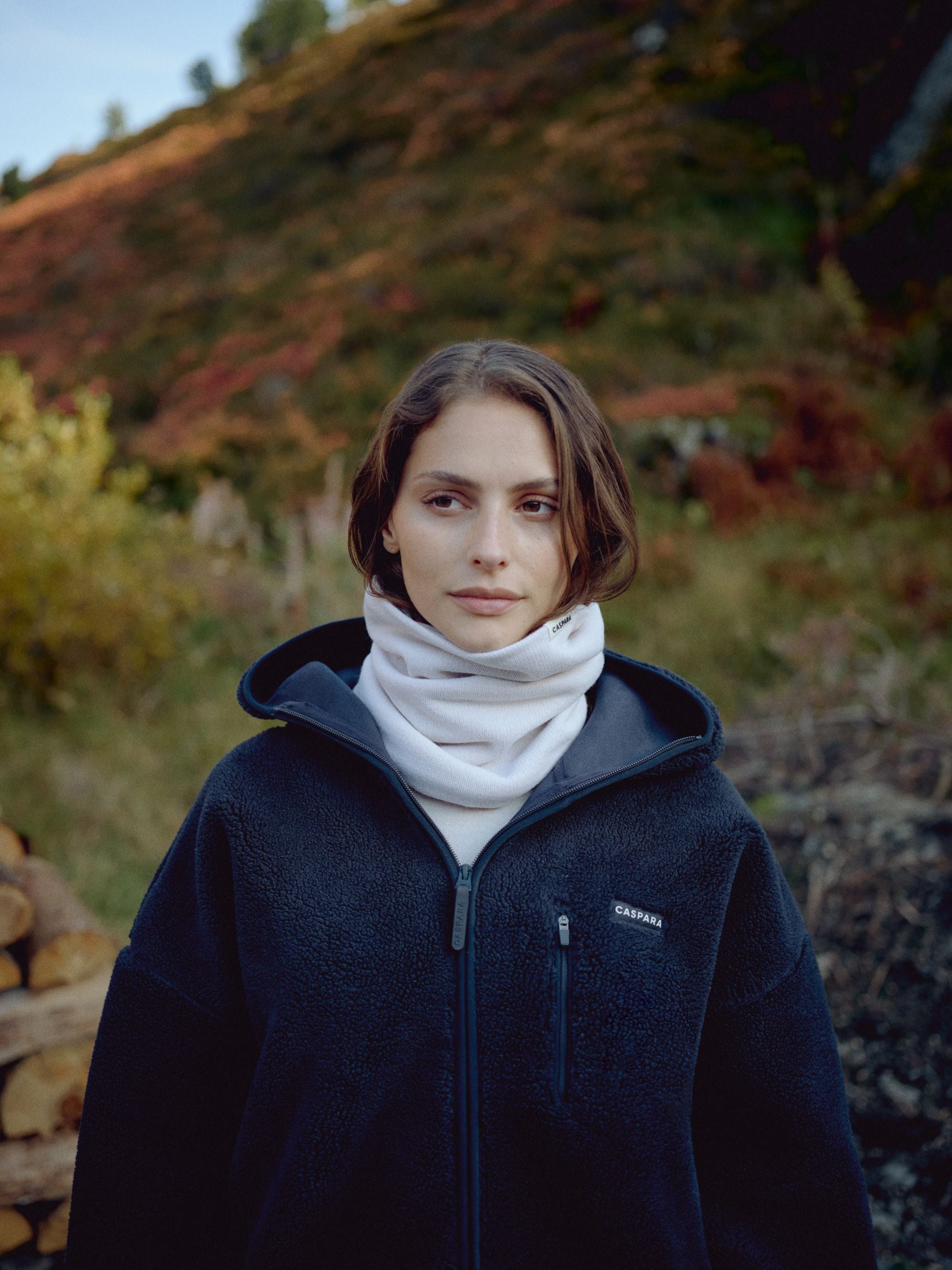 Woman wearing a creme CASPARA Classic Neckwarmer and fleece jacket outdoors.