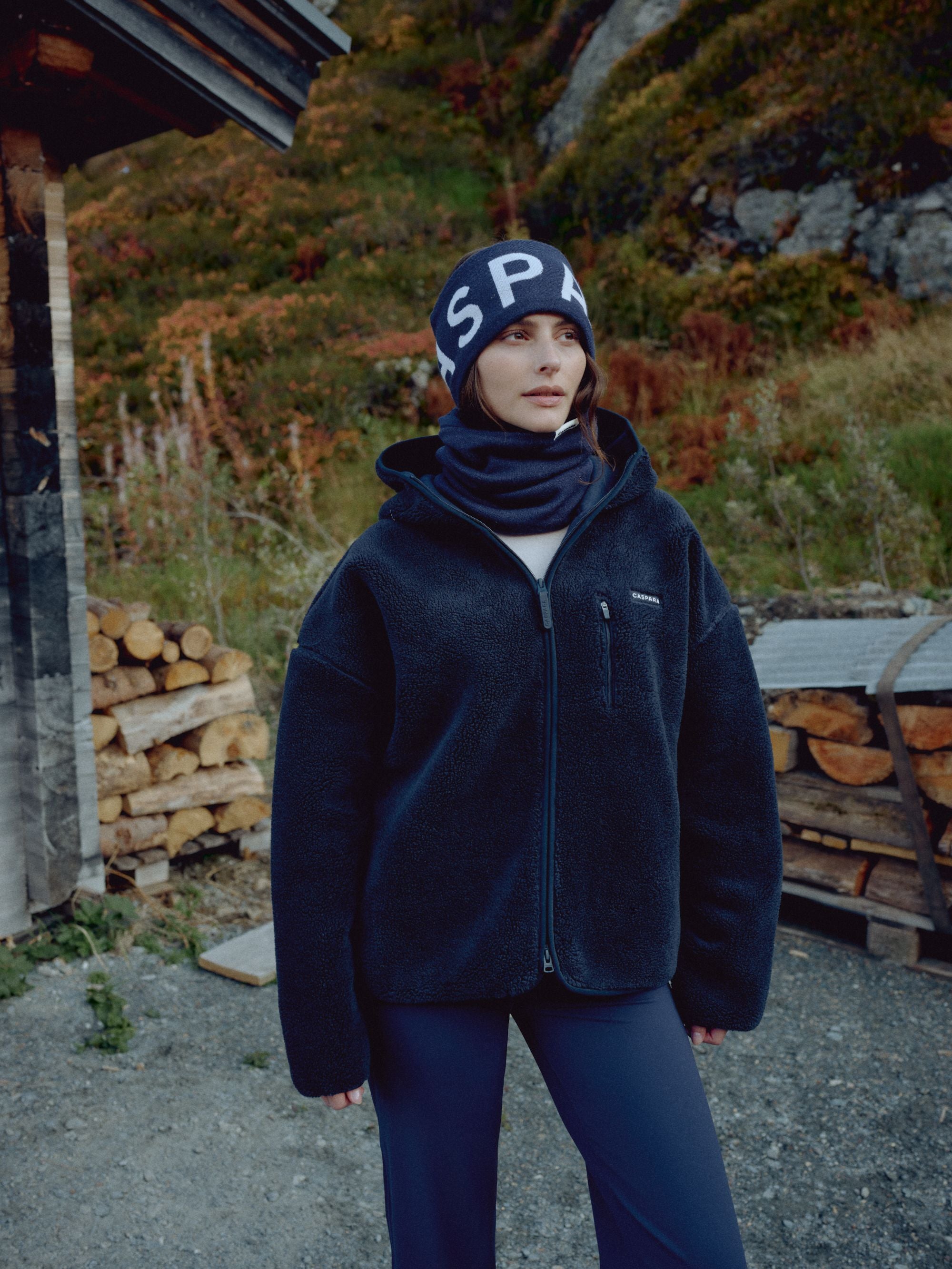 Woman wearing a navy CASPARA SKI headband and fleece jacket outdoors.