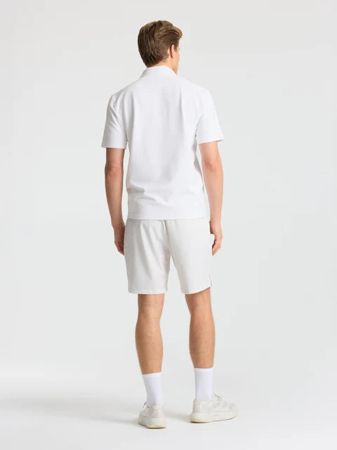 Back view of a man wearing white CASPARA Prime Core shorts and a white polo shirt.