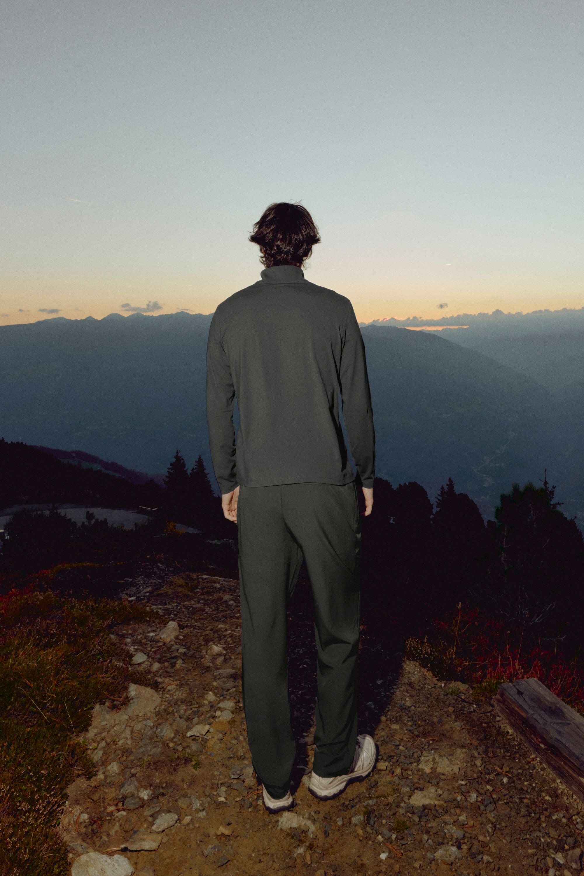 Man wearing olive green CASPARA Prime Core pants overlooking a mountain landscape.
