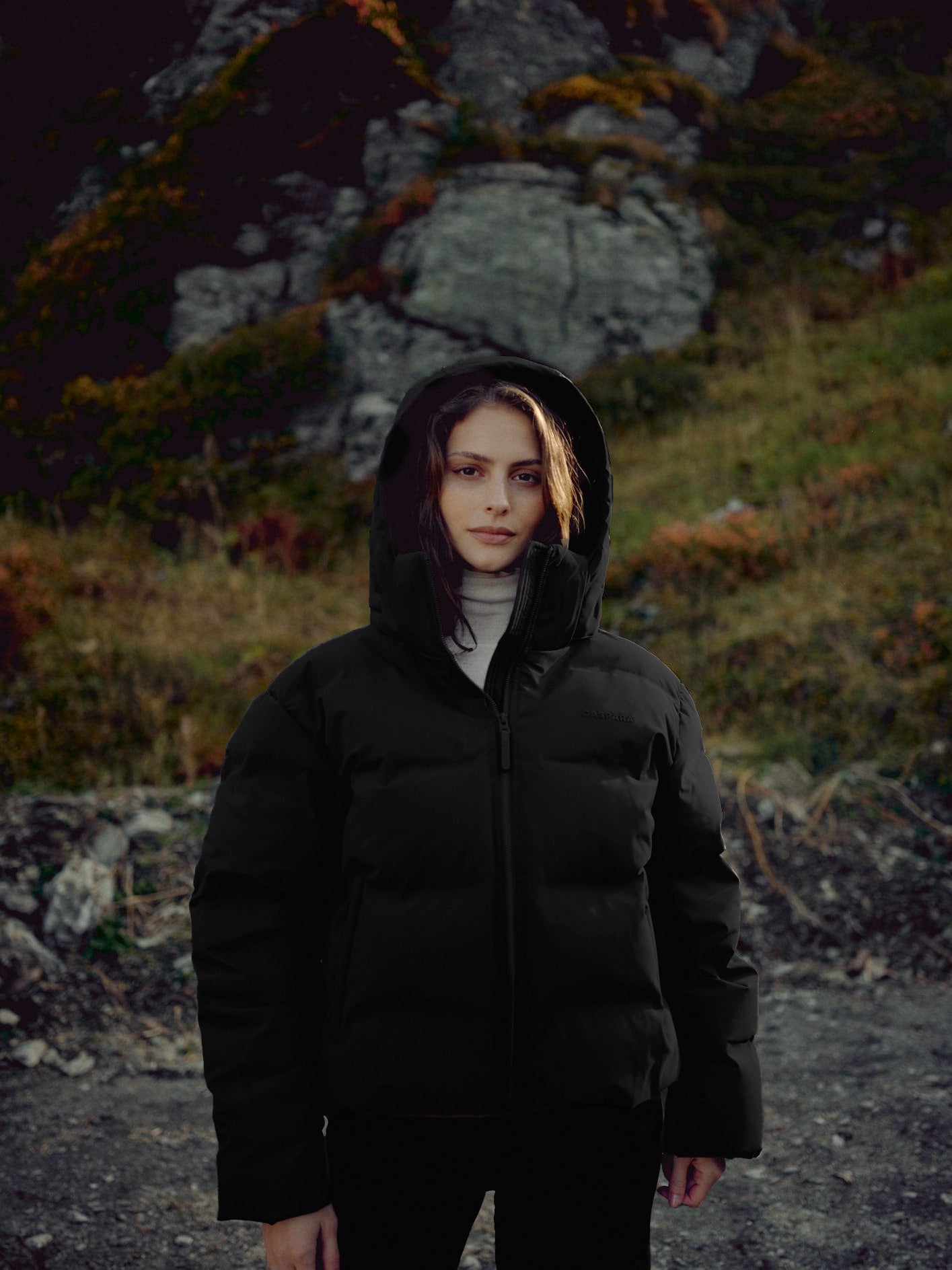 Woman wearing a black CASPARA Aurora hooded puffer jacket outdoors.