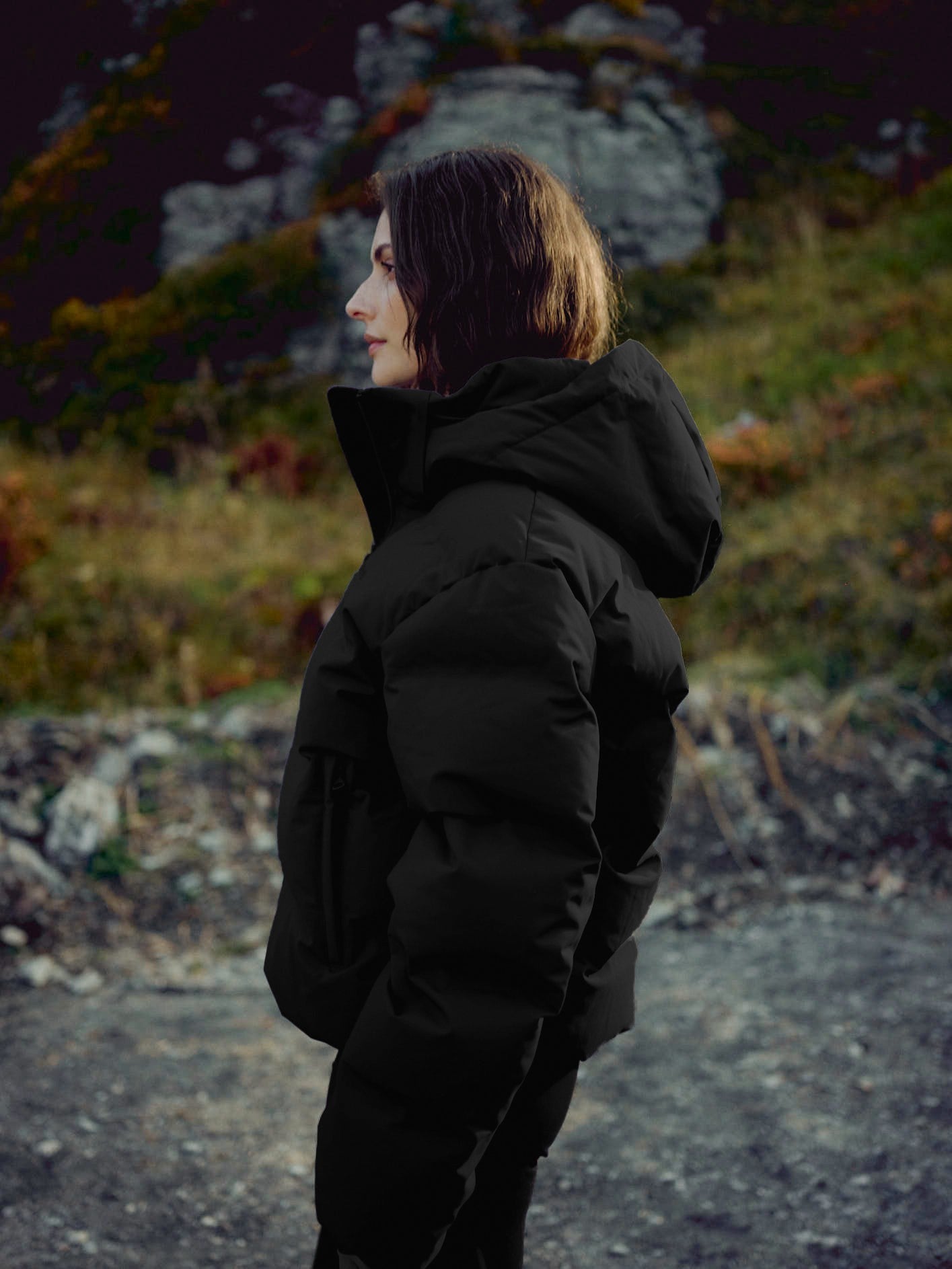 Side view of a woman wearing a black CASPARA Aurora puffer jacket outdoors.